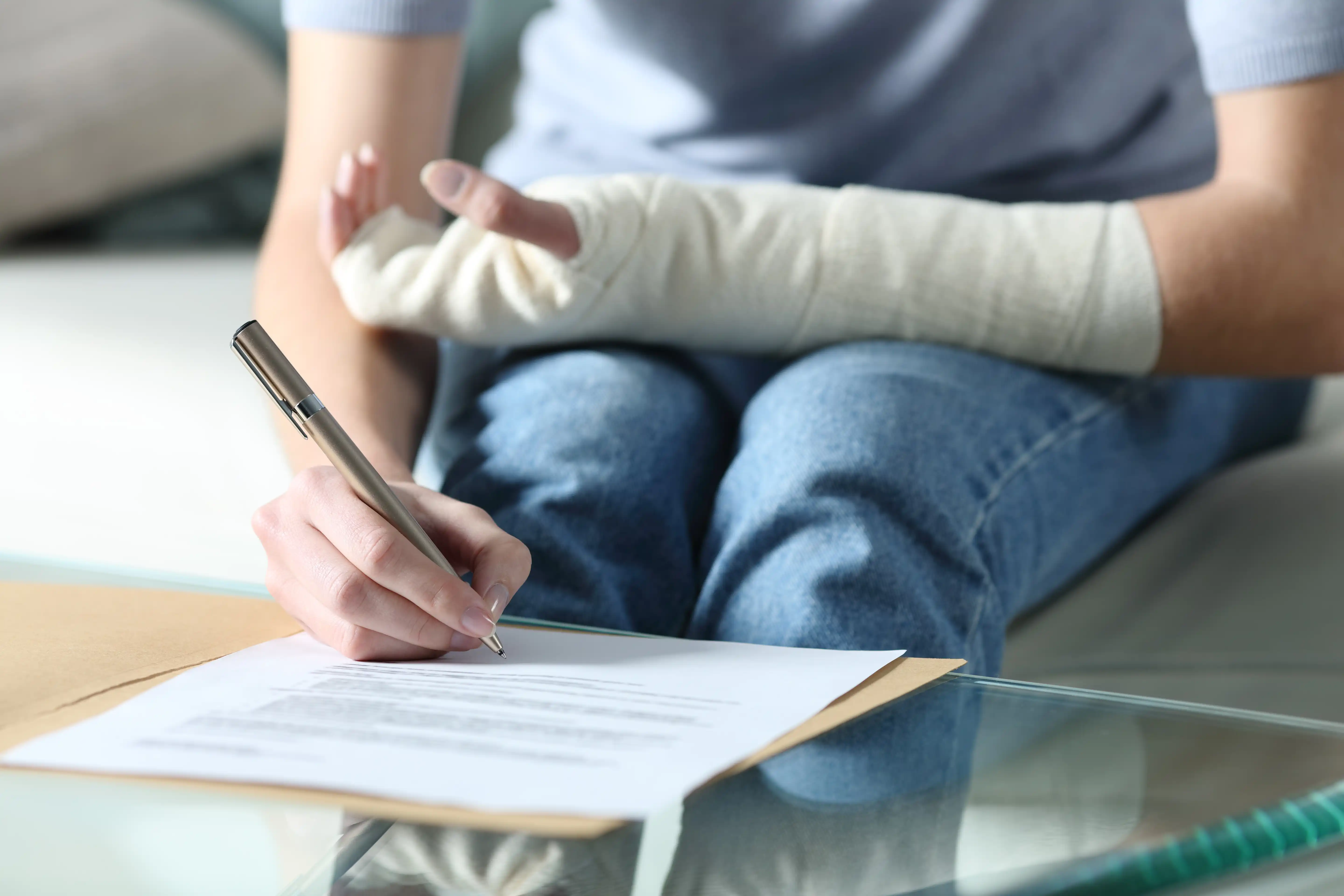 An injured person with a cast on their wrist filling out medical leave paperwork, illustrating how to give notice to an employer under CFRA