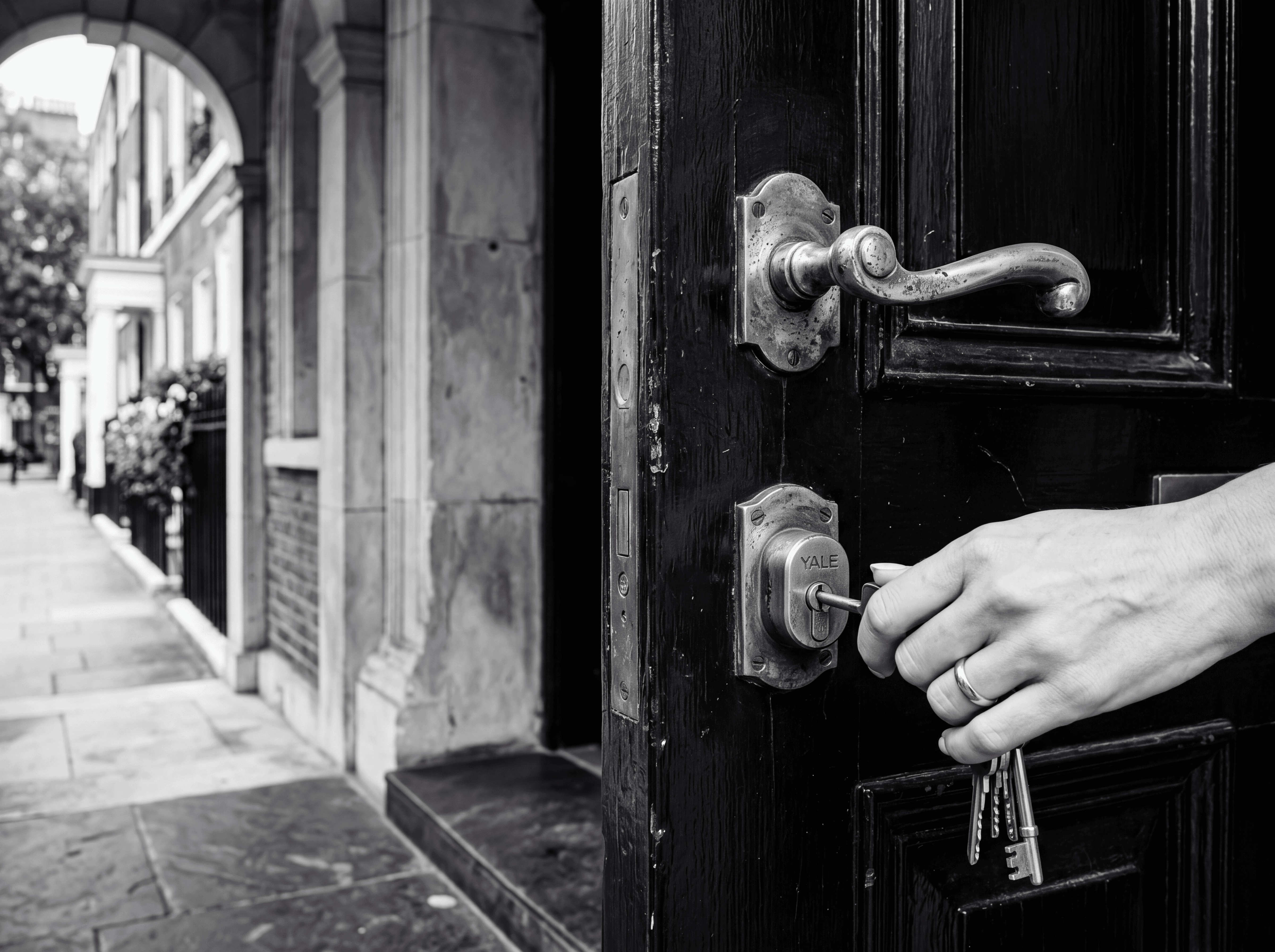 Antique brass door handle on a black Georgian townhouse door with polished doorstep, illustrating the London property purchase process for Russian-speaking buyers, monochrome editorial photograph