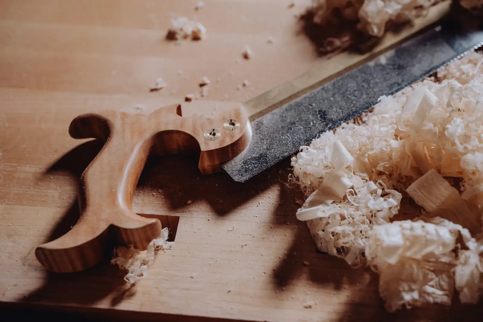 A chisel and pale wood shavings on a workbench