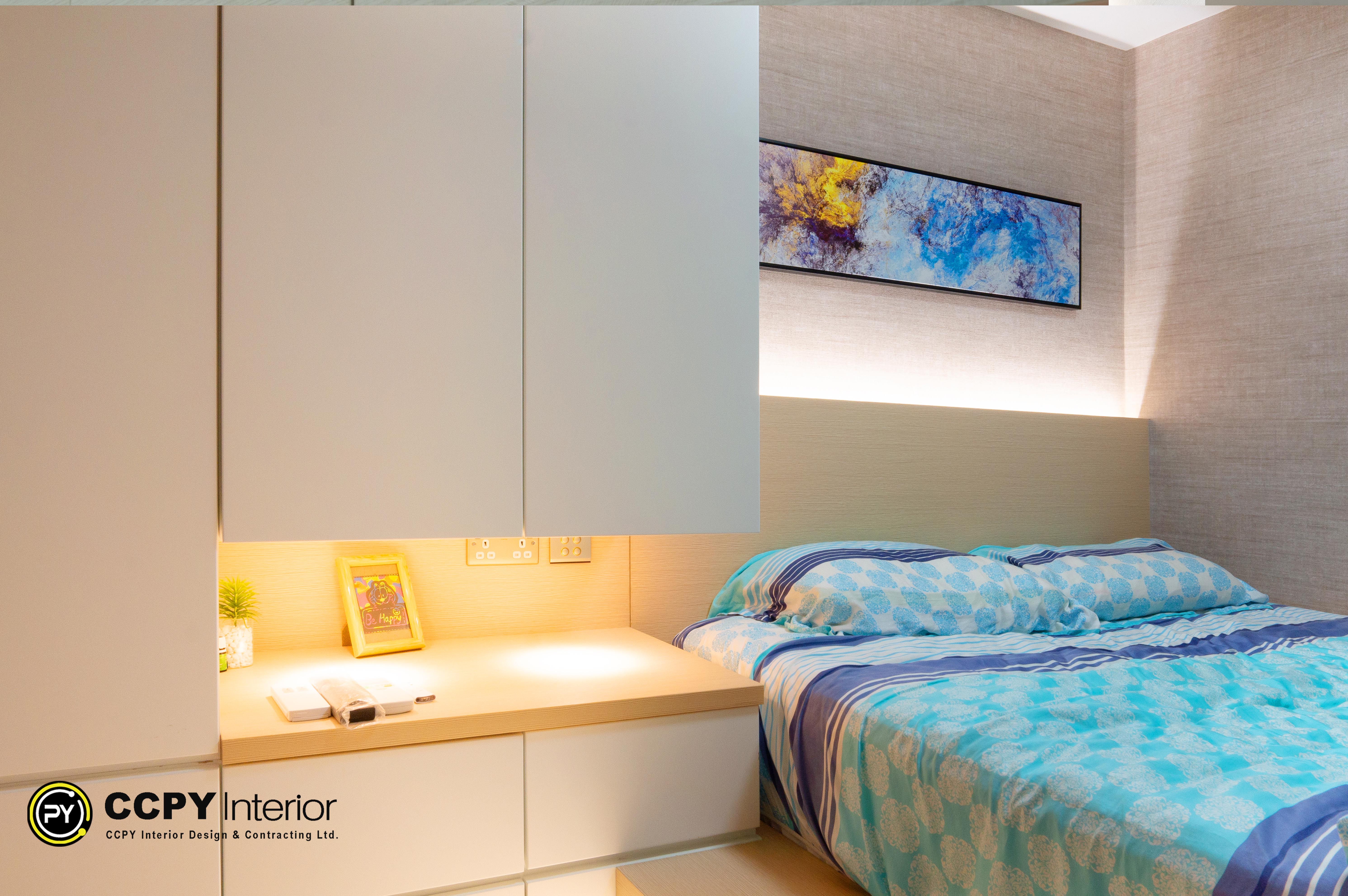 The selected region displays a smart bedroom design by CCPY Interior, showcasing a custom-built bed, integrated desk, and overhead storage units designed for a compact Hong Kong apartment.Here is a detailed breakdown of the interior design features and the unit details visible in the project notes:Bedroom Design FeaturesSmart Space Planning: Custom-built cabinetry maximizes vertical space with overhead storage directly above the study desk.Integrated Lighting: Warm LED strip lighting under the upper cabinets and behind the headboard illuminates the workspace and bed without harsh glare.Warm Contemporary Aesthetic: Light wood veneers and matte off-white finishes create an airy, modern, and welcoming atmosphere.Multifunctional Desk: The built-in desk serves as a bedside table while offering a dedicated workspace equipped with easily accessible power outlets.