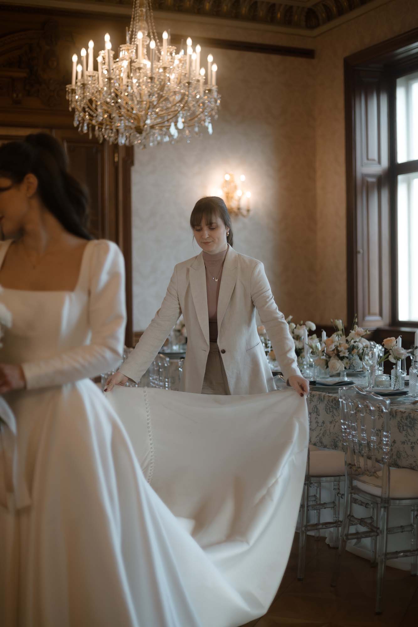 Hochzeitsplanerin Emily richtet die Schleppe des Brautkleides.