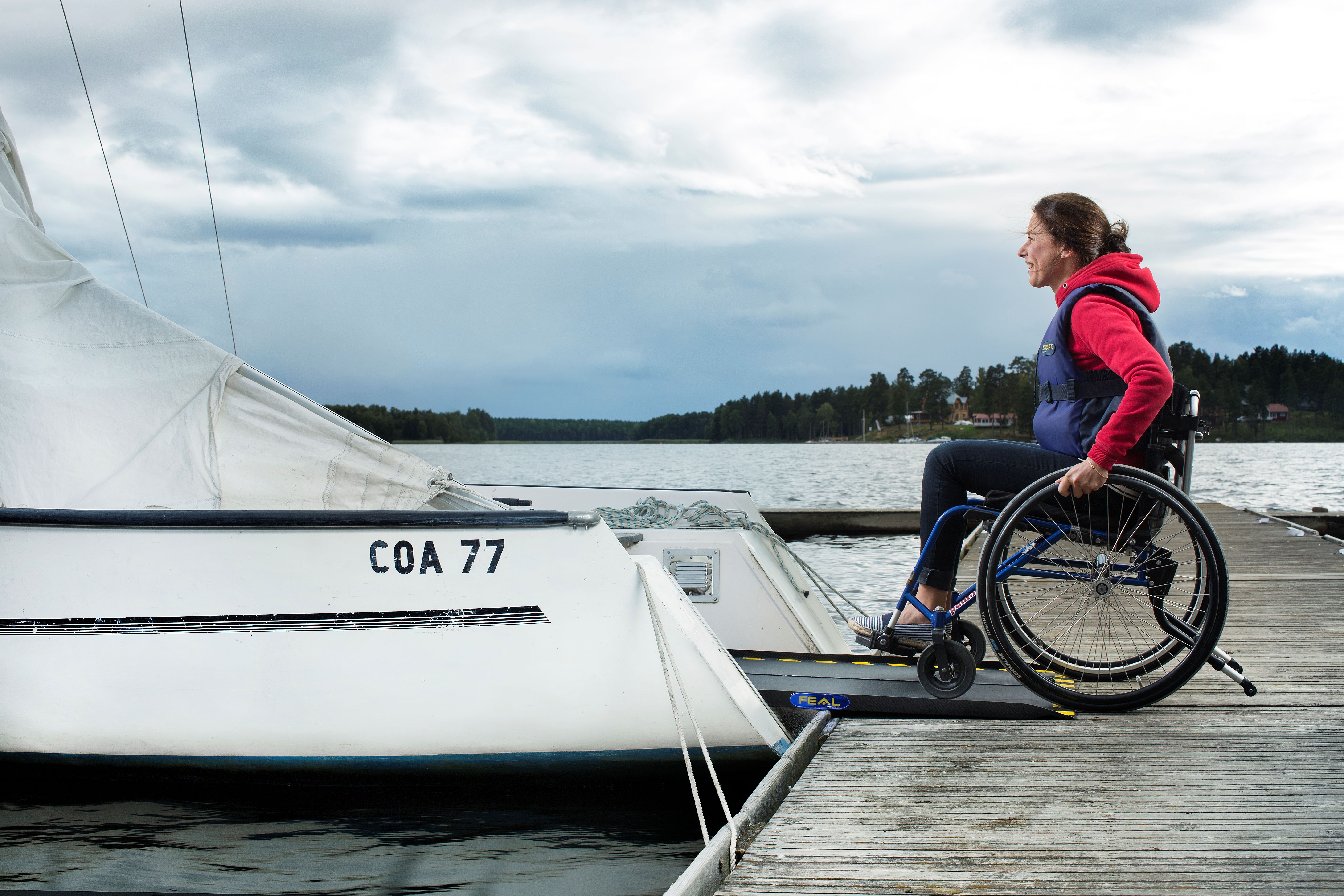 A manual wheelchair user entering a sailboat using a carbon fiber wheelchair ramp by Feal