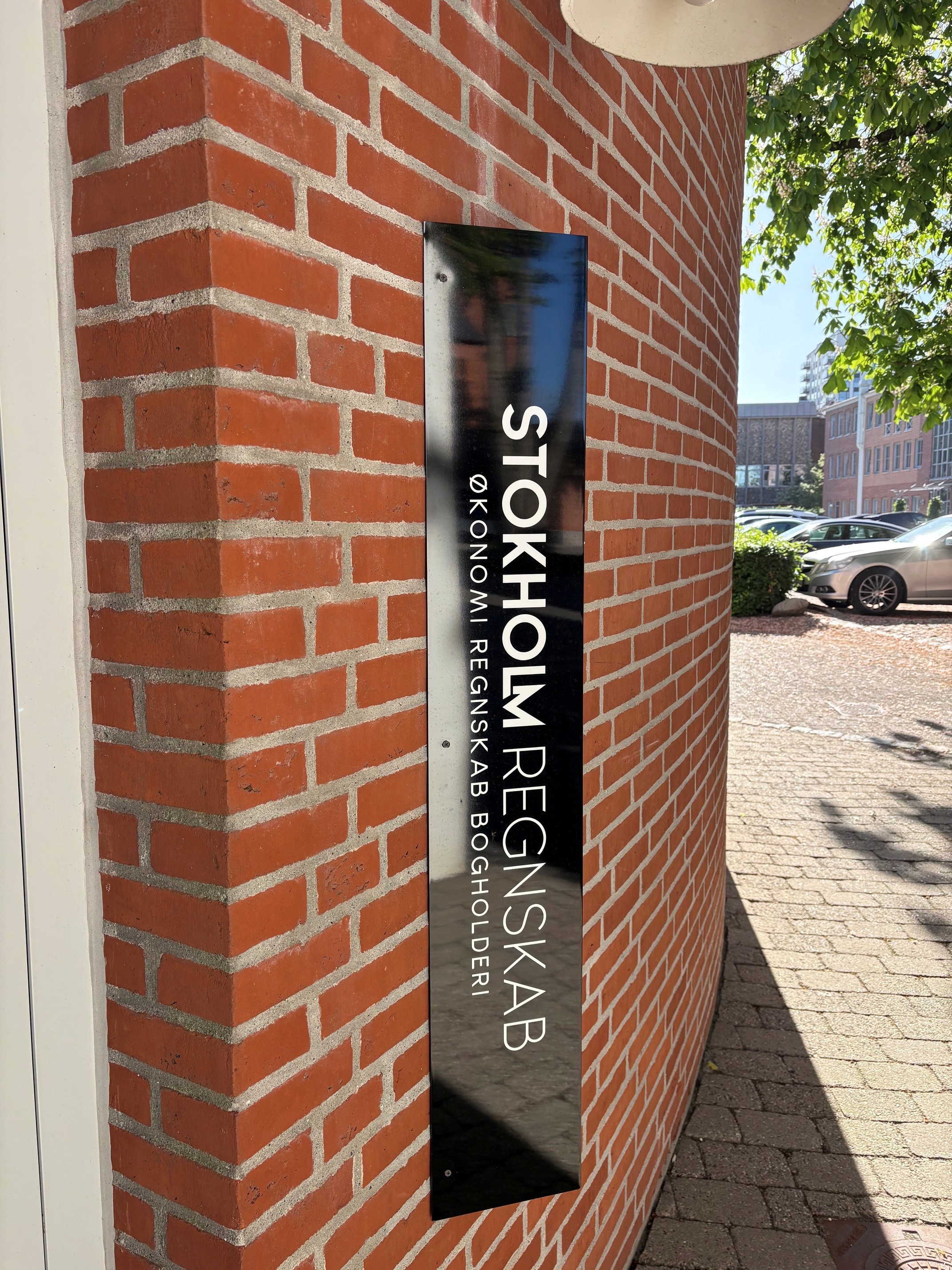 Udendørs skilt ved Stokholm Regnskab i Herning med økonomi, regnskab og bogholderi på murstensfacade