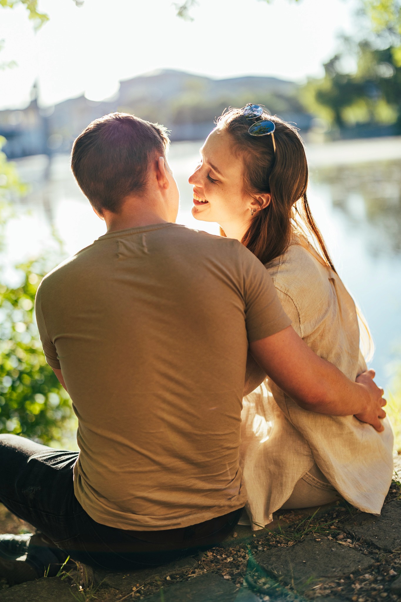 Egy pár ül a városligetben a tóparton, egymáshoz közel, természetes környezetben.