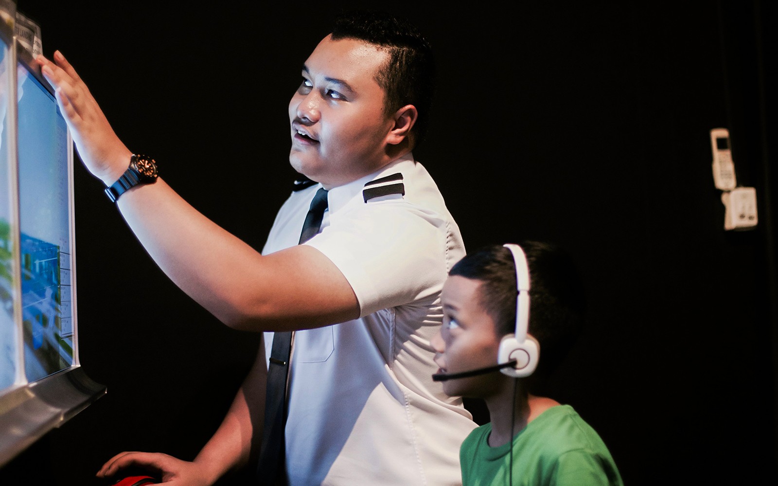 在航空全飞行体验中，飞行员在飞行模拟器中指导儿童。