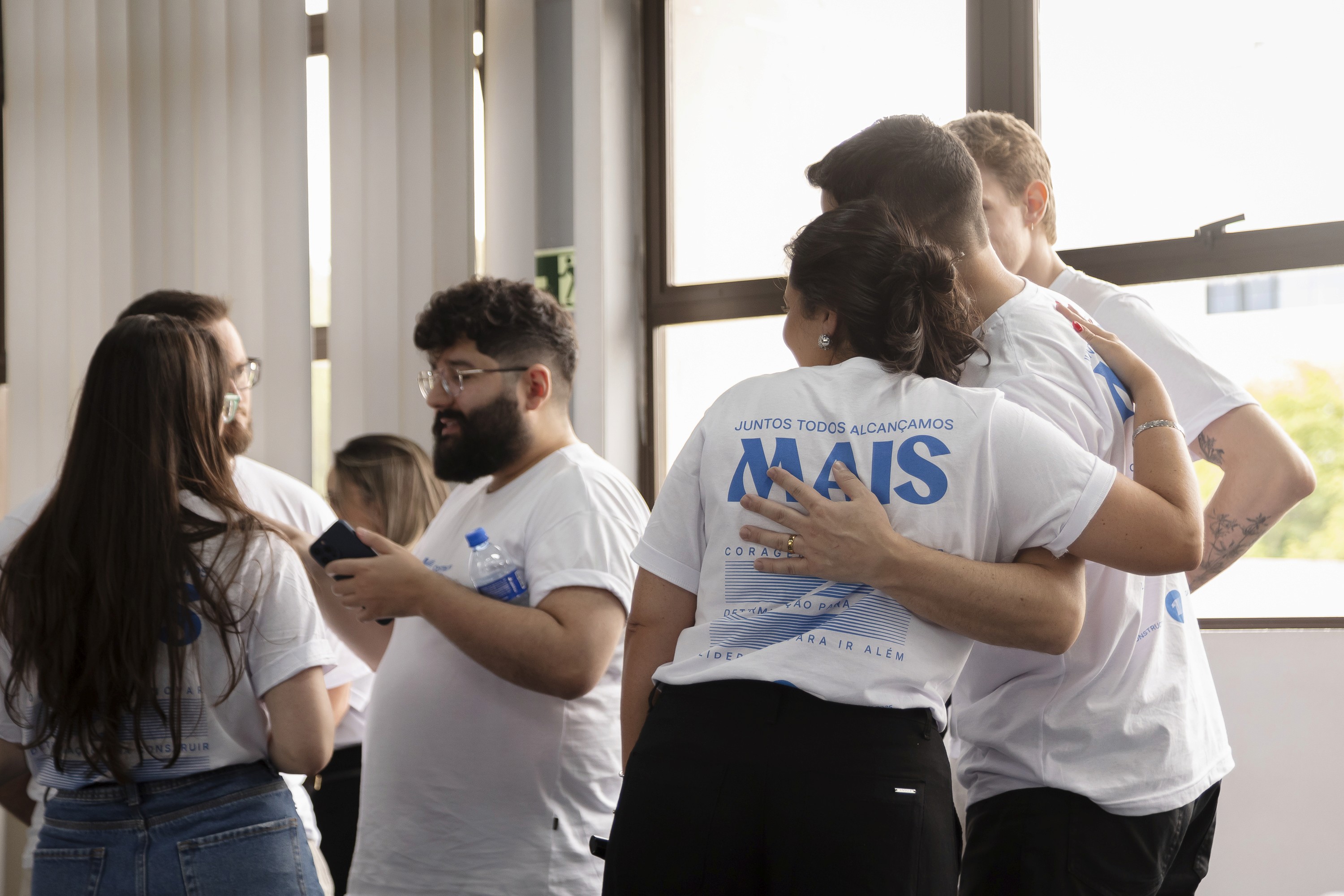 Colaboradores da Construct IN em uma mesa de reunião, em um evento interno. Uma mulher no primeiro plano está escrevendo em um papel com a frase 'PLANO DE AÇÃO', em uma dinâmica de grupo.