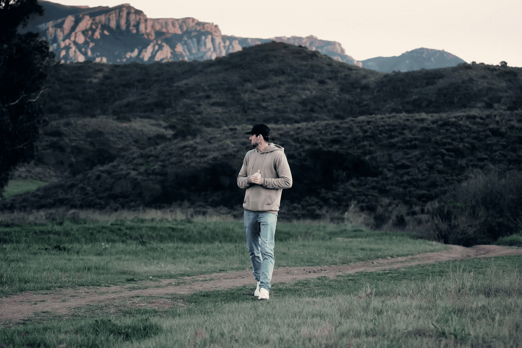 a man standing on a dirt road in a field