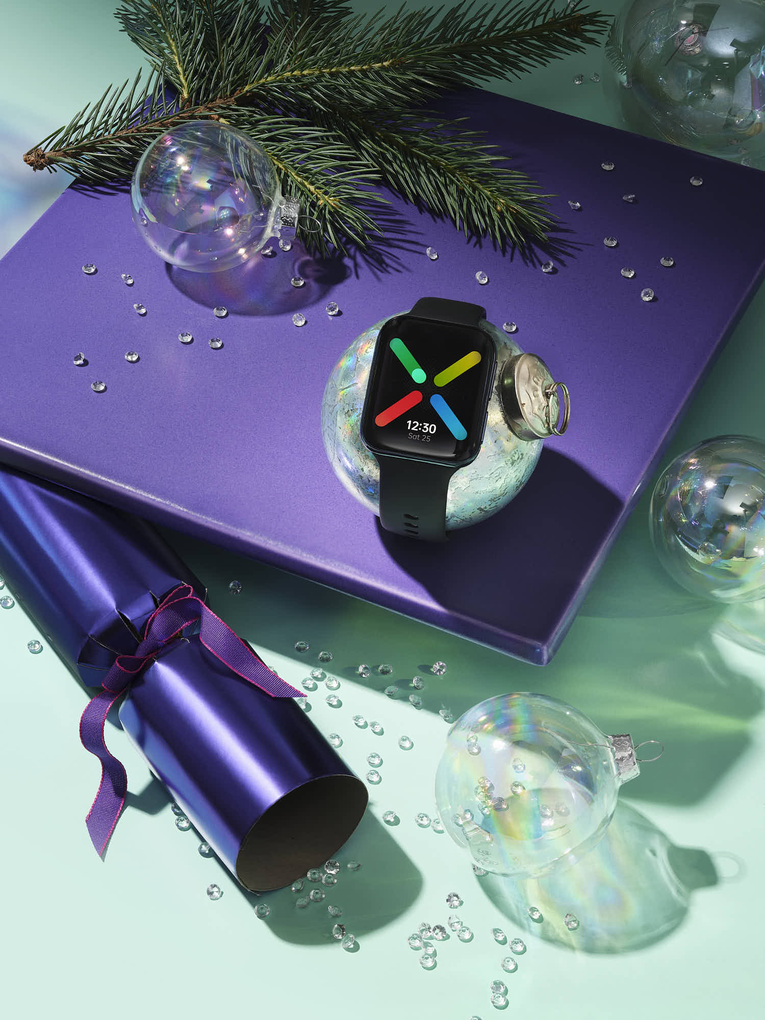 Smartwatch on a purple gift box amid holiday decorations and fir branches.
