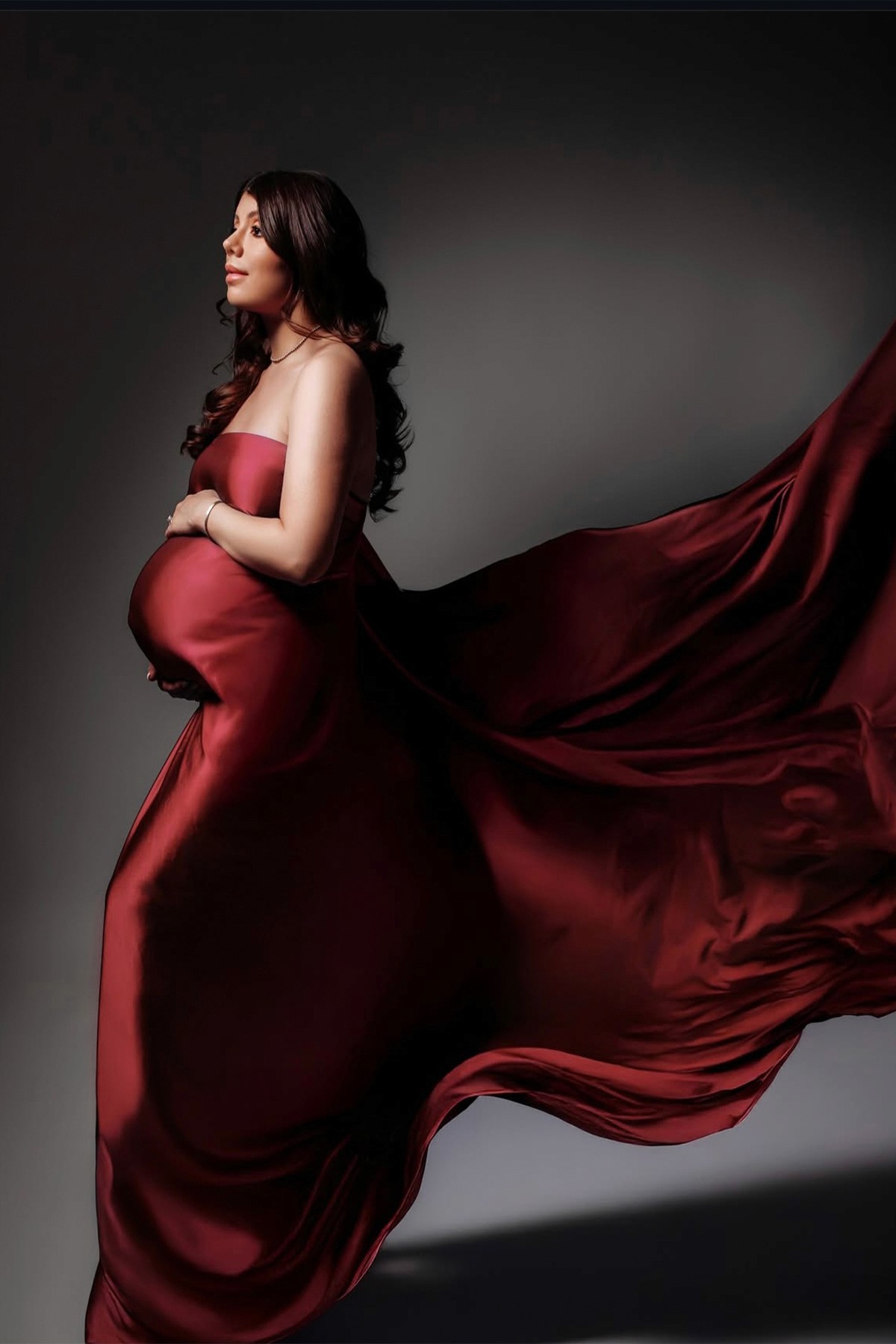 Pregnant woman in a soft silk gown — light and graceful maternity portrait.