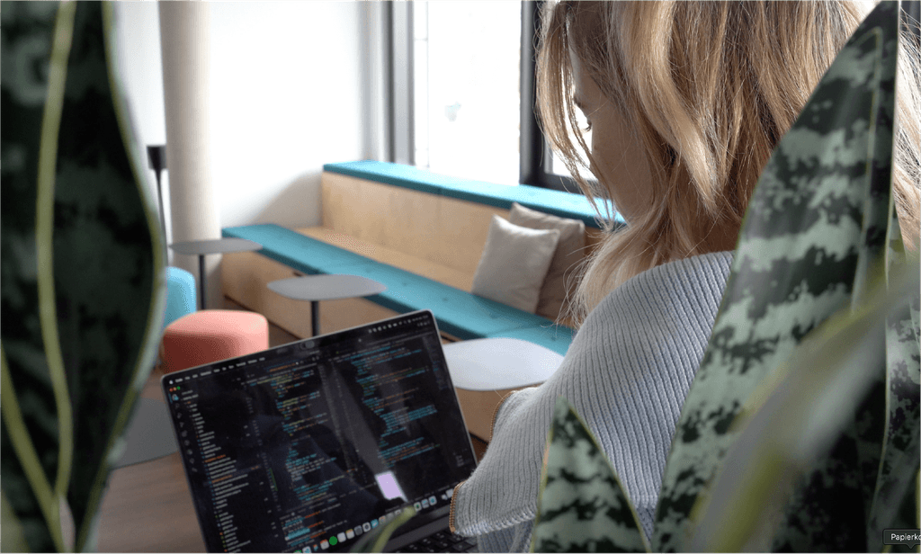 Eine Frau sitzt in einer modernen Lounge und programmiert etwas am Laptop