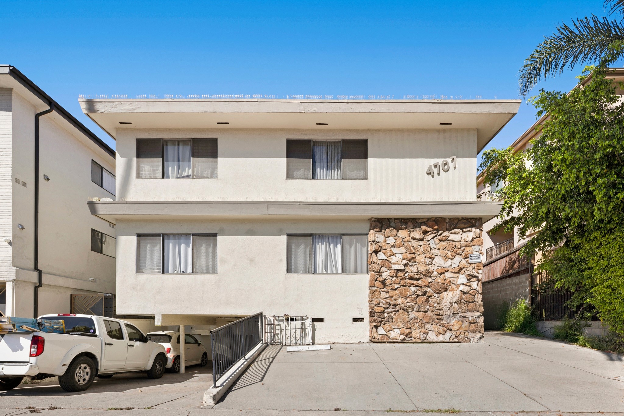 Front exterior of two-story multifamily building with stone facade at 4707 Beverly.