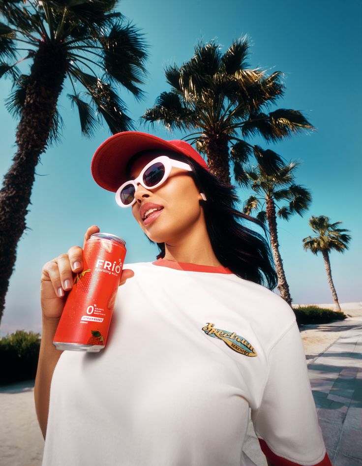 A black Leica camera with a textured body is dramatically lit in red, reflecting on a glossy surface. The red background adds a bold, intense mood.