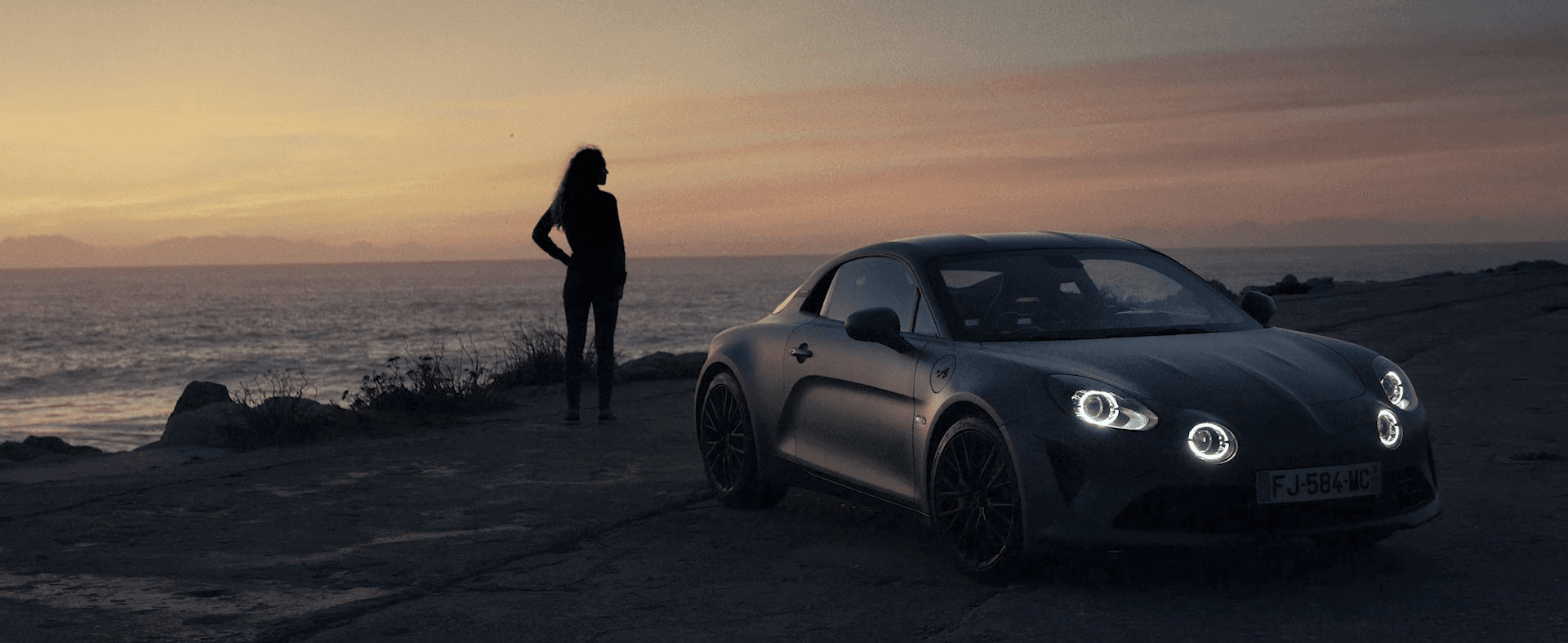 A person stands on a street corner at night.