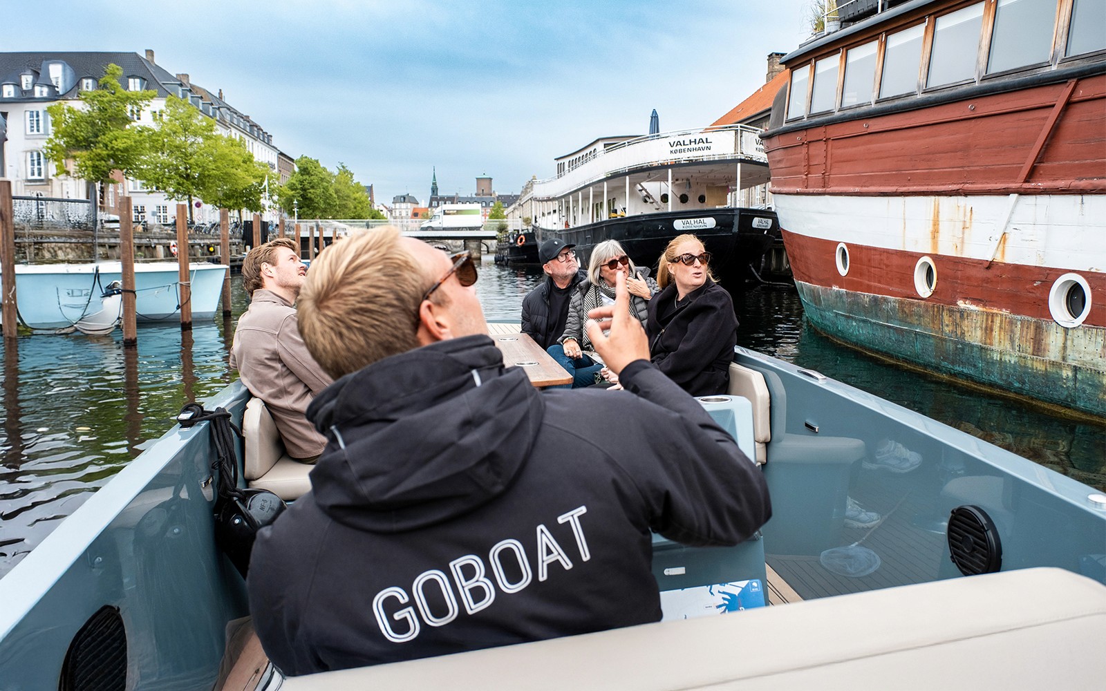 Vendégek egy elektromos hajótúrán Koppenhágában, miközben a város nézelődnek a kapitány pedálozik.