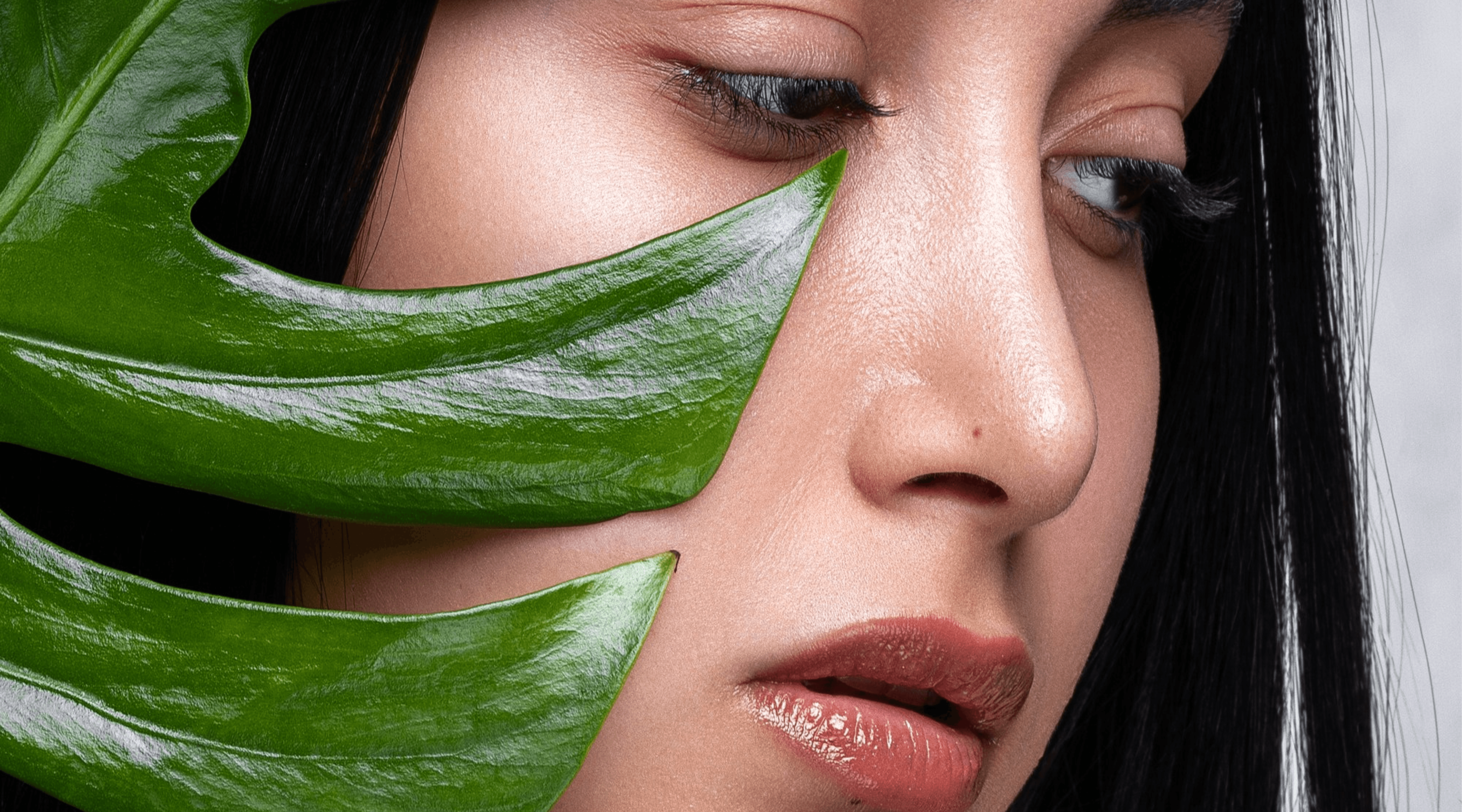 Woman's face next to a green leaf.
