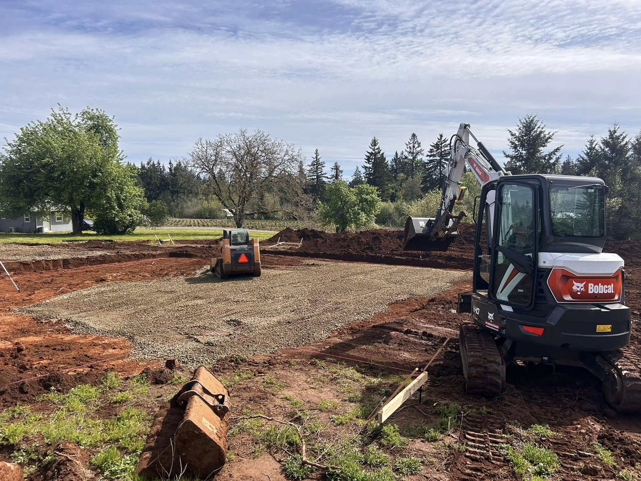 Excavator clearing muddy dirt for commercial site prep in Oregon City