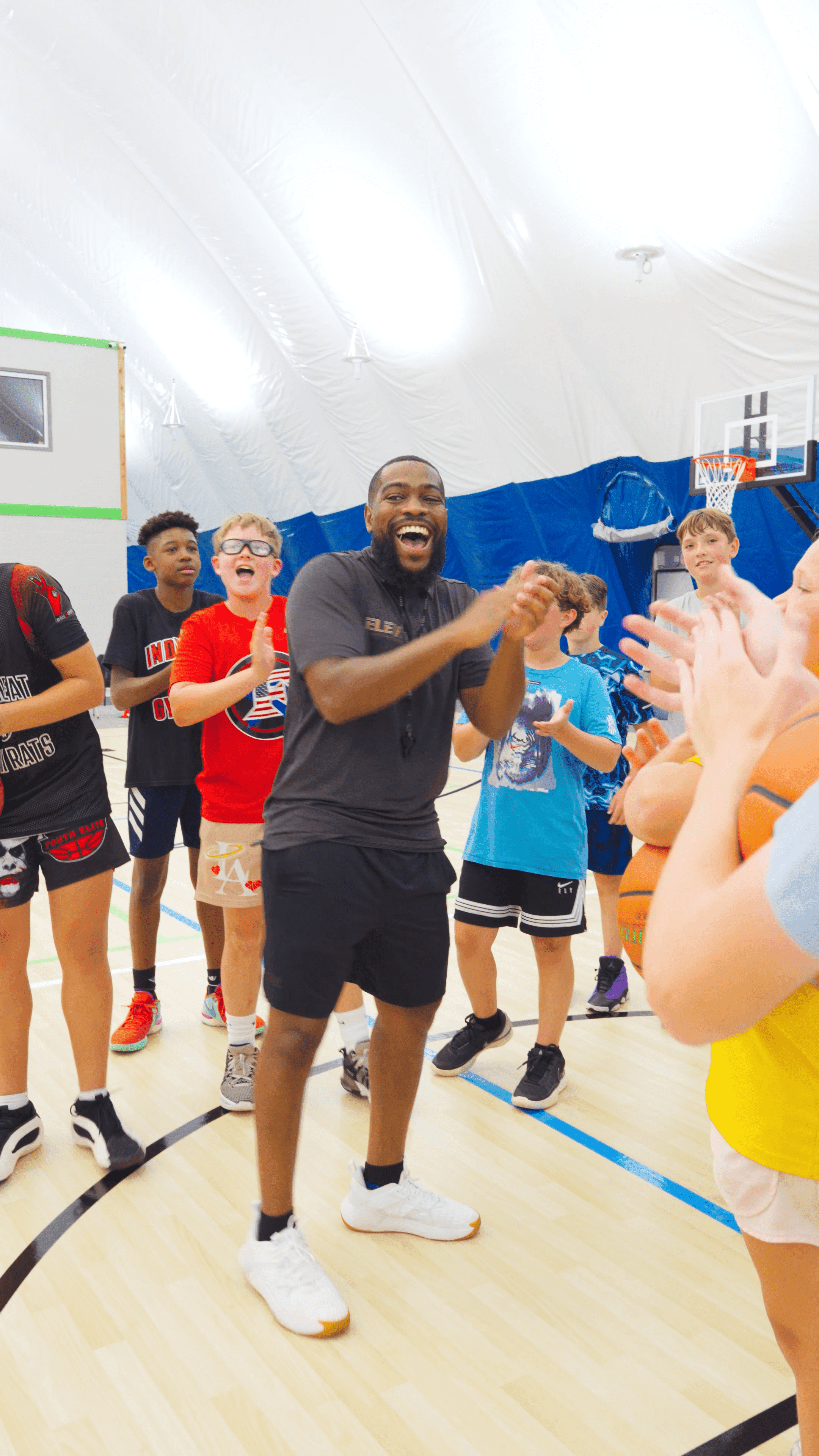 Group of teenagers applauding and cheering while a coach leads or encourages them.