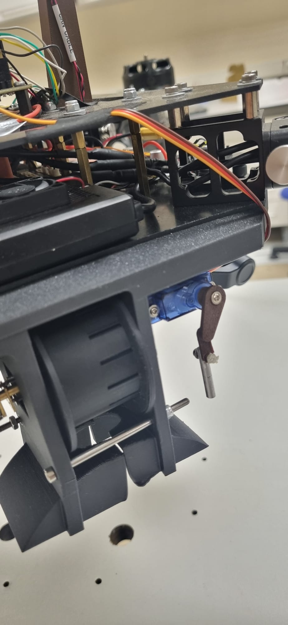 The assembled plate stack, photographed from the side. The spacers standing between the two plates are the load-bearing members described here, and the wiring runs through the gap they open. The photograph also shows a servo and a mechanism below the lower plate that this document does not describe.
