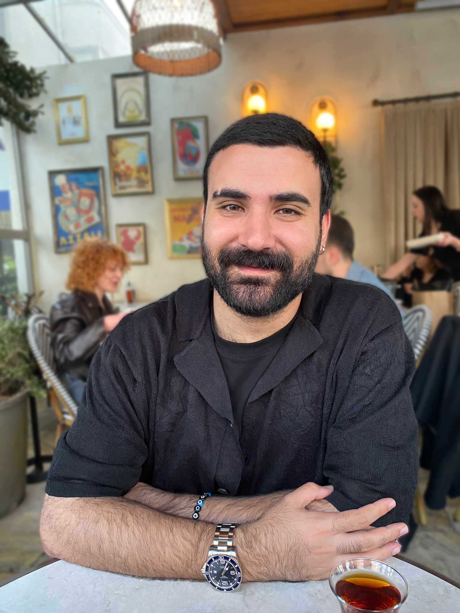 Person wearing a blue puffer jacket and red backpack standing in front of a light blue building on a city street.