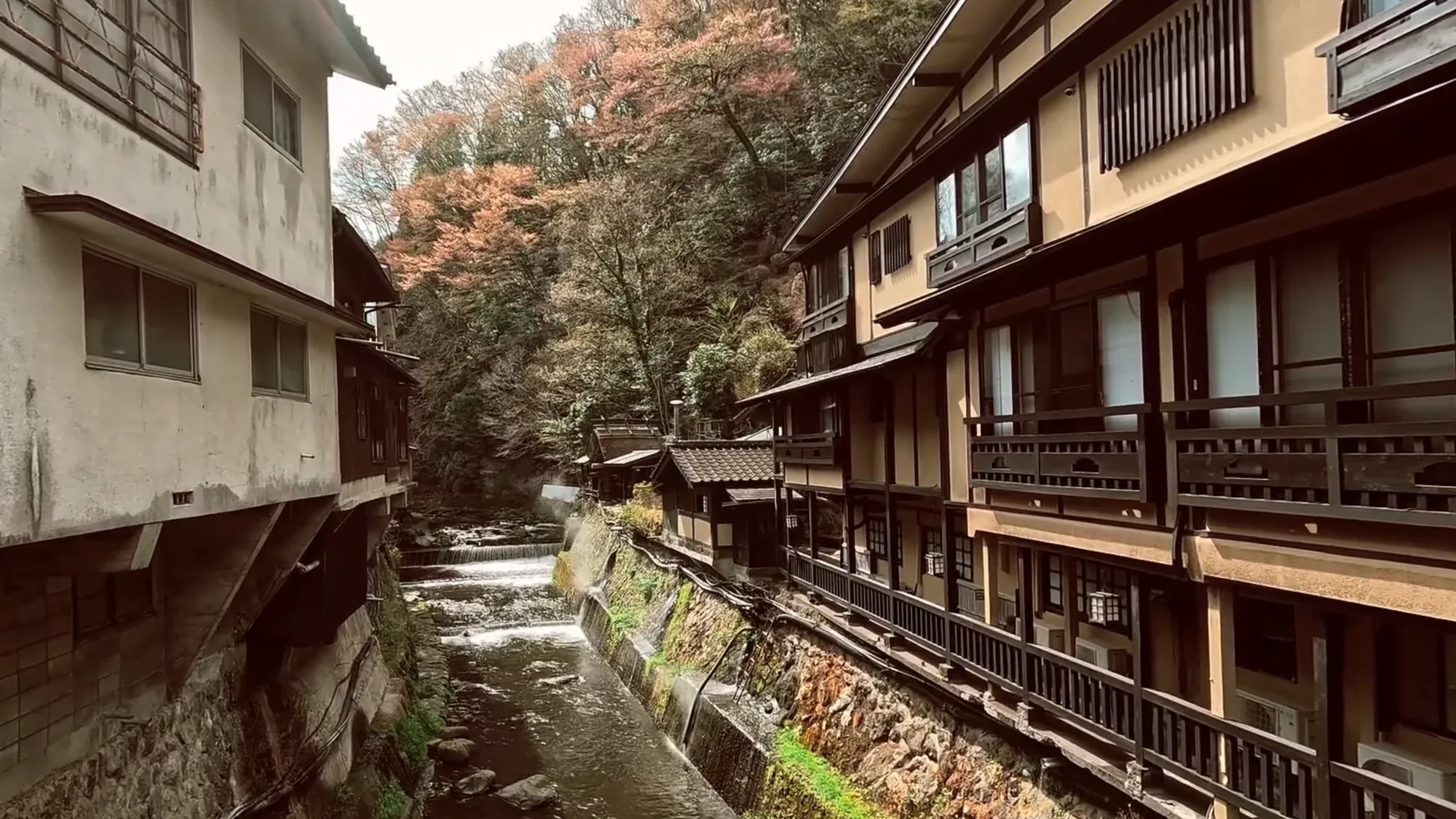 The narrow river running between inn walls at Kurokawa Onsen in autumn