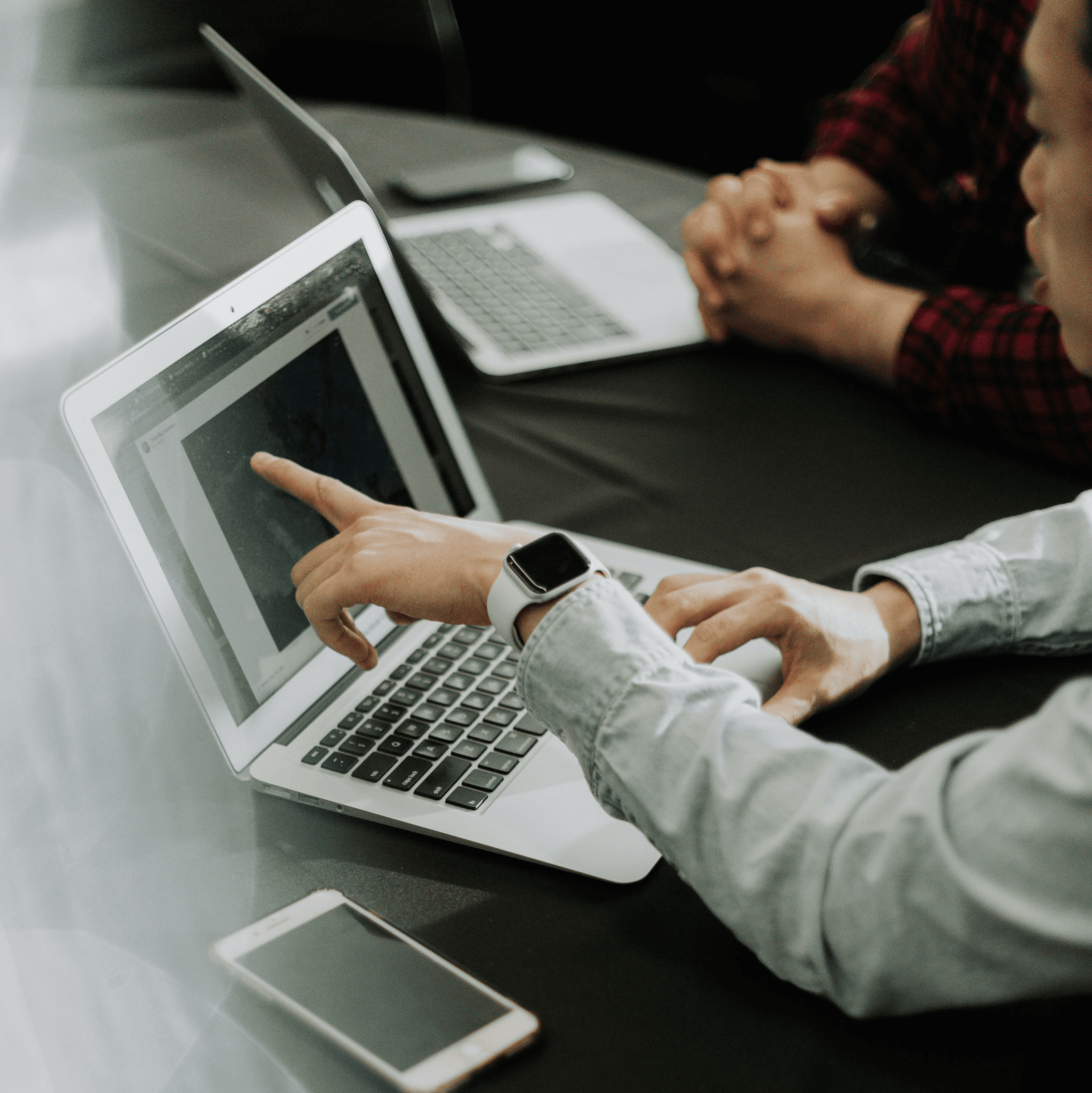 two people sitting at a table with laptops