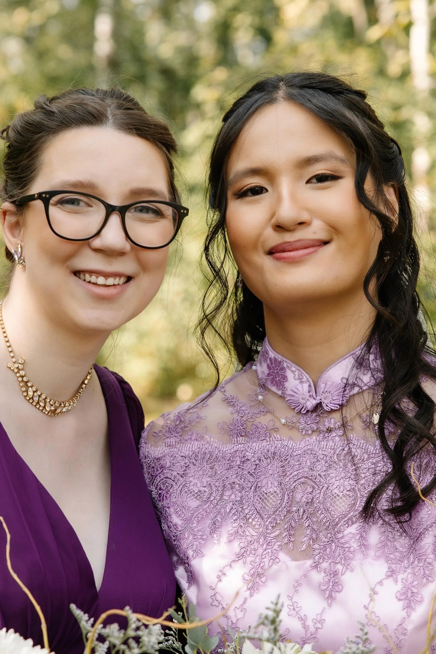 A couple stands hand-in-hand in front of a rustic stone building.