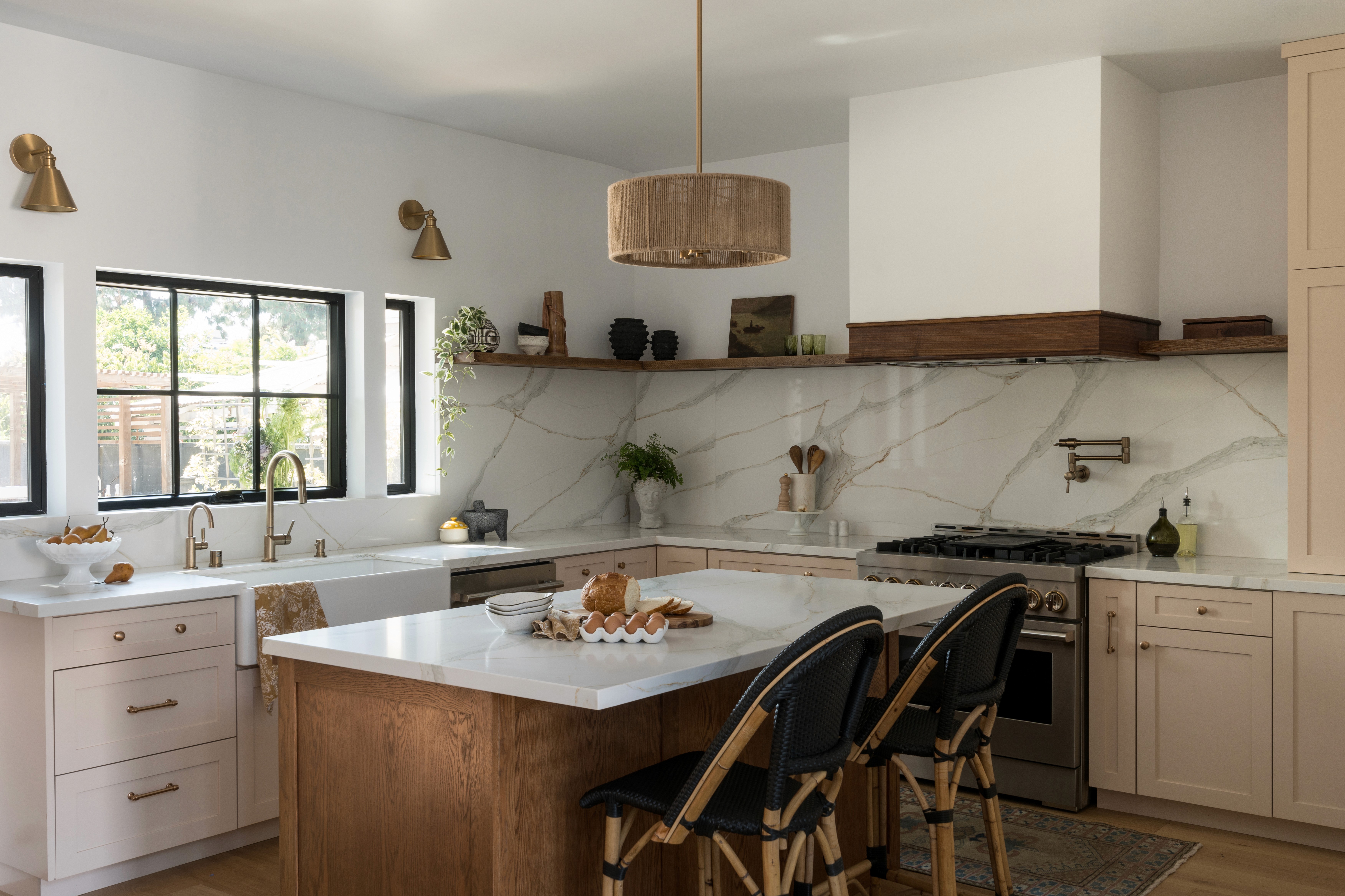 A bright and feminine kitchen featuring white countertops, soft pastel accents, and modern cabinetry. The space is designed with clean lines, a central island for gathering, and plenty of light, creating an inviting atmosphere by Jubilee Interiors in Lakewood, California