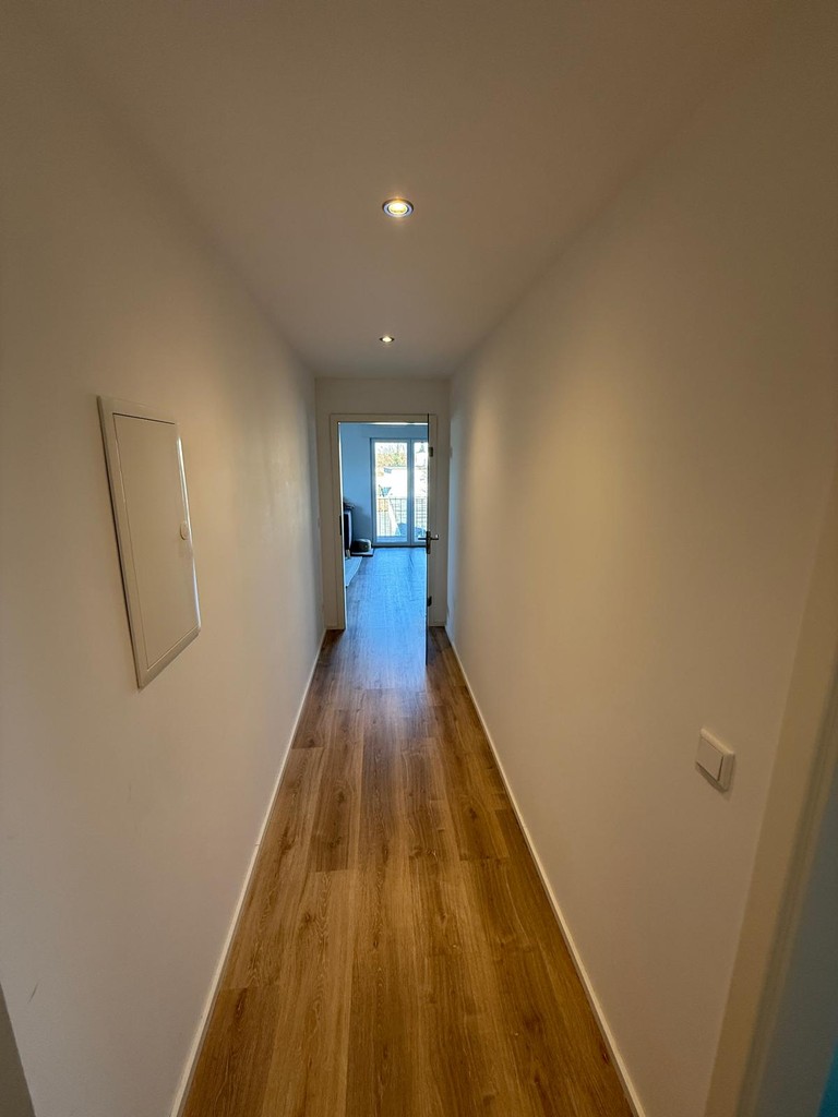 Flur im sanierten Dachgeschoss mit neuem Bodenbelag, heller Wandgestaltung und moderner Beleuchtung