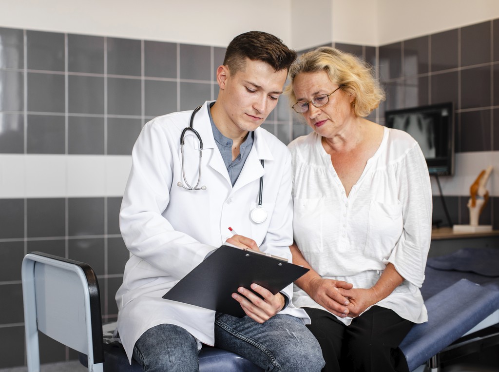 Silhouette of a researcher examining a slide under a microscope with a blue background.
