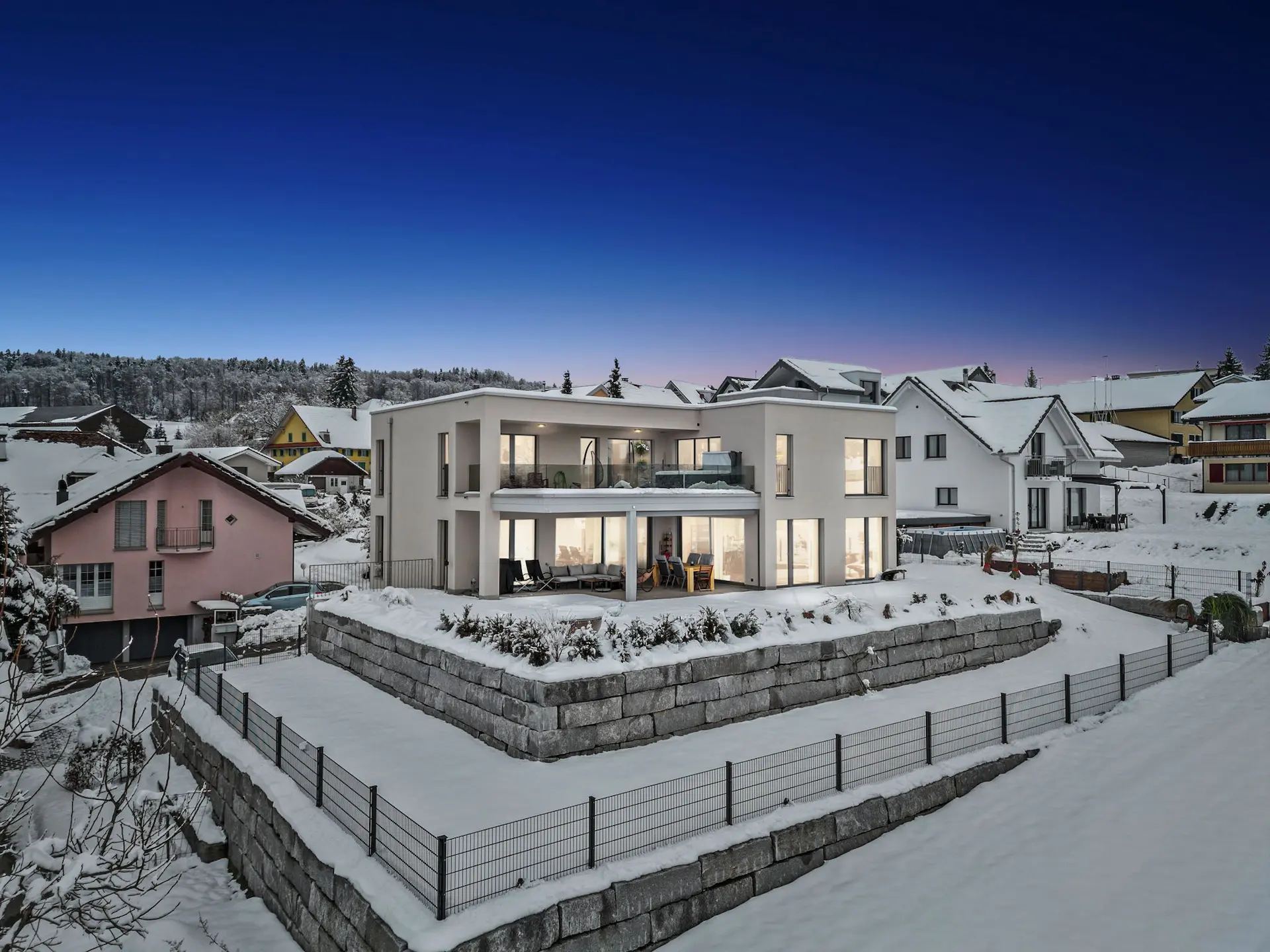 Gesamtansicht der Immobilie bei winterlicher Abendstimmung mit verschneitem Garten