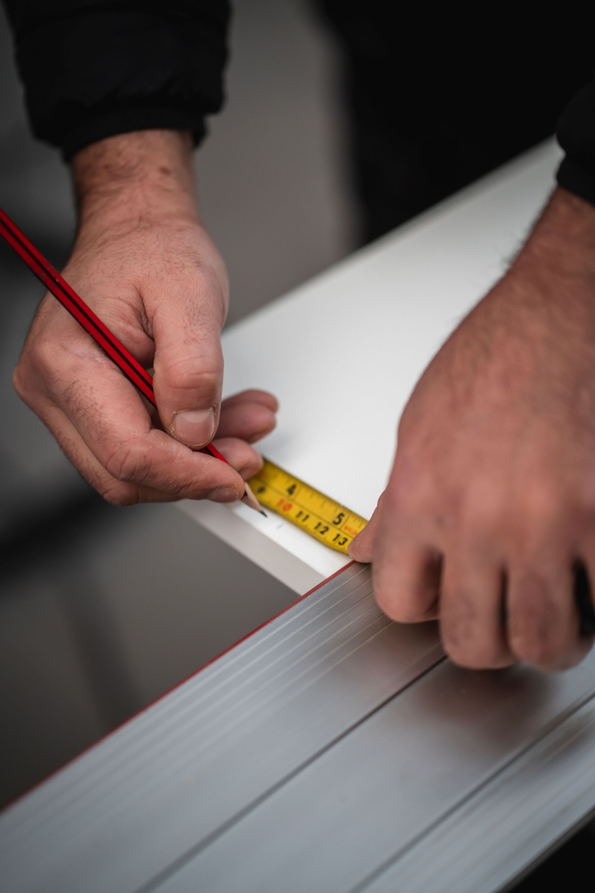 close-up angle of a man mesauring and marking a piece of wood