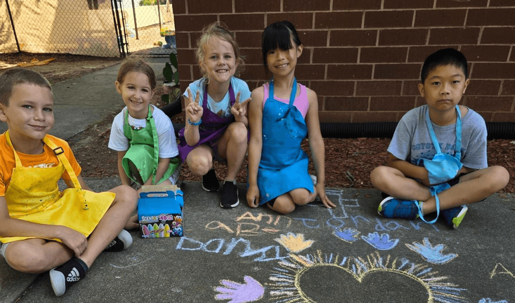 Summer campers doing sidewalk art outside of the SportPlus Charlotte facility 