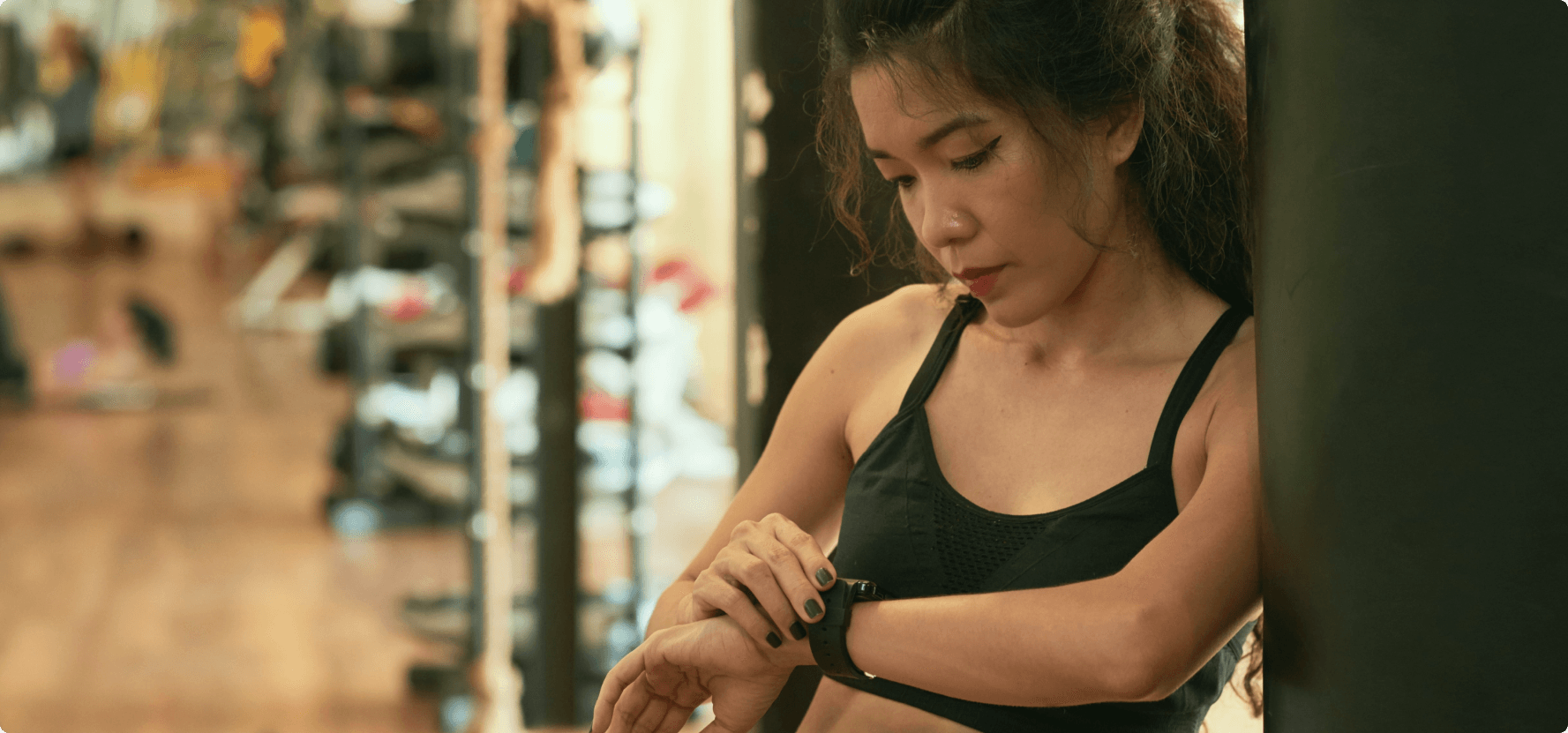 A woman in the gym looking at her smartwatch.