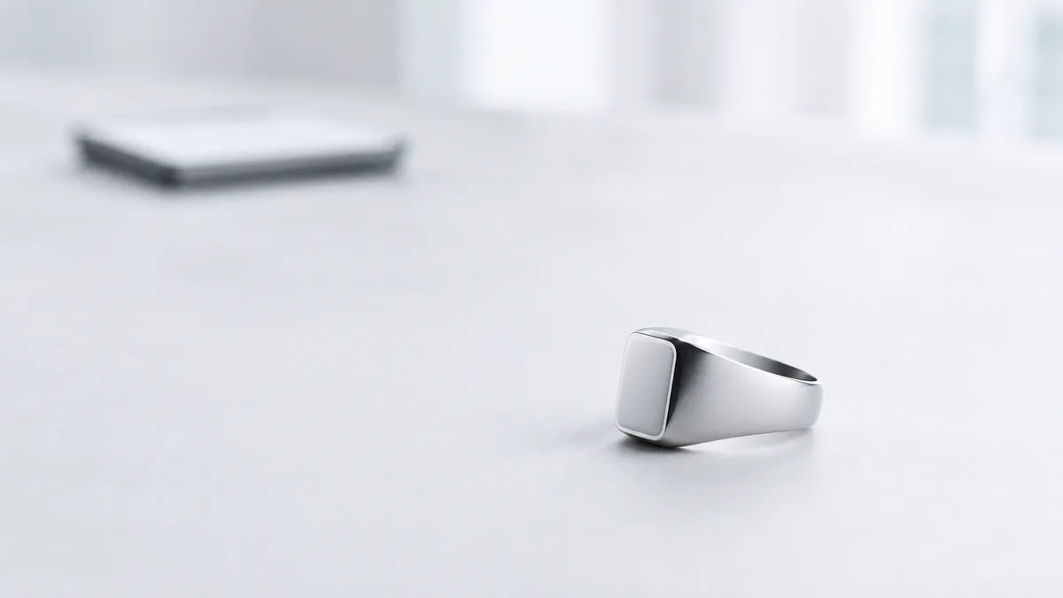 Silver smart tasbih ring in sharp focus with a blank-screen phone blurred far in the background