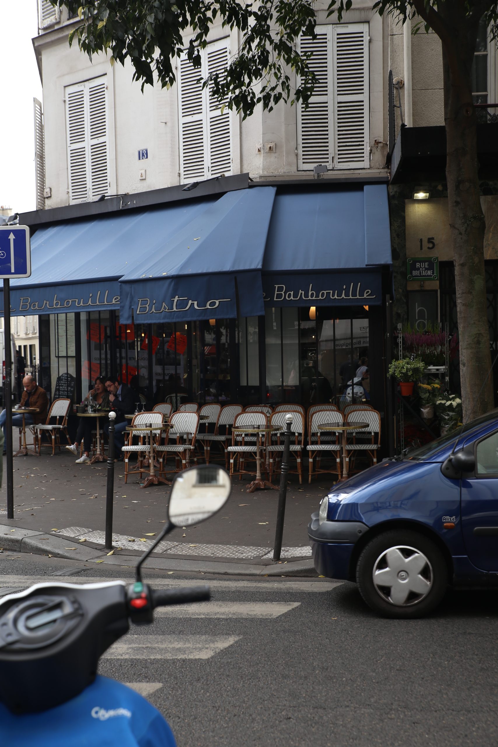 Le Barbouille bistro on a Paris street corner with outdoor cafe seating and striped awnings
