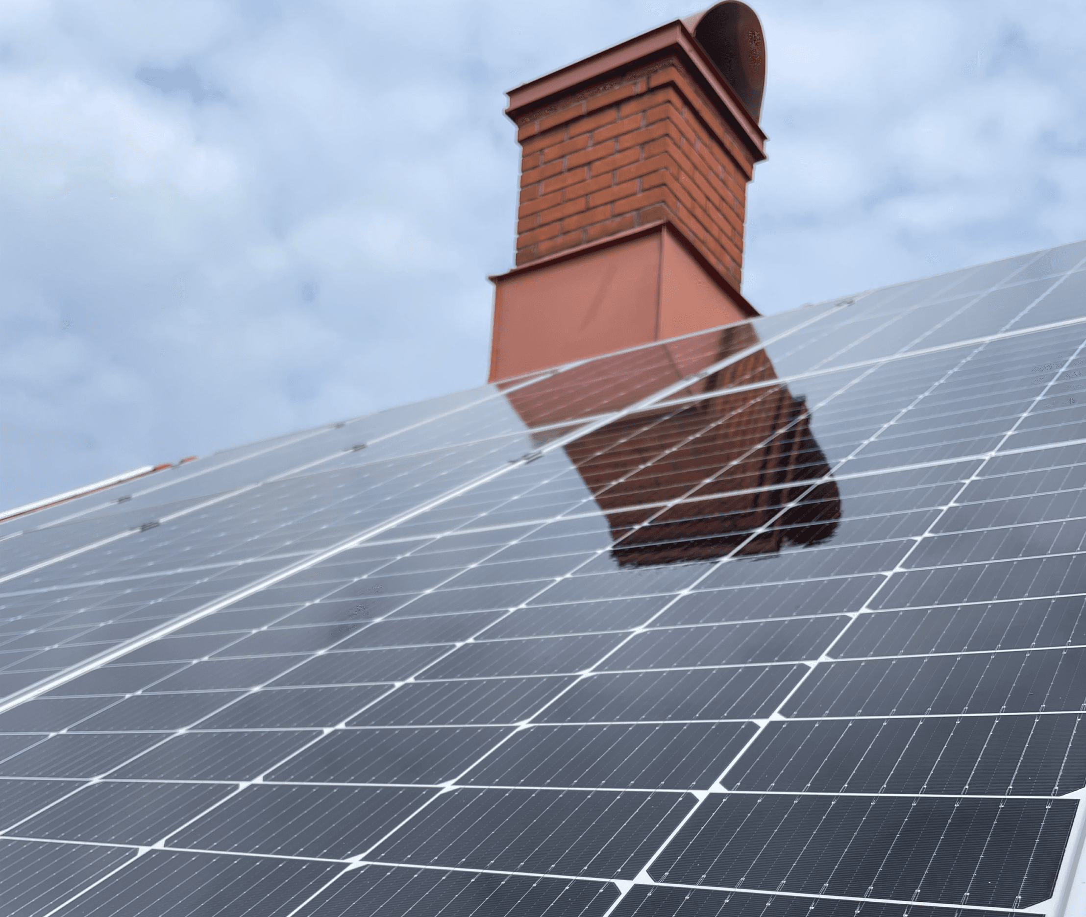 Bild på ett hustak med blänkande solceller och en skorsten