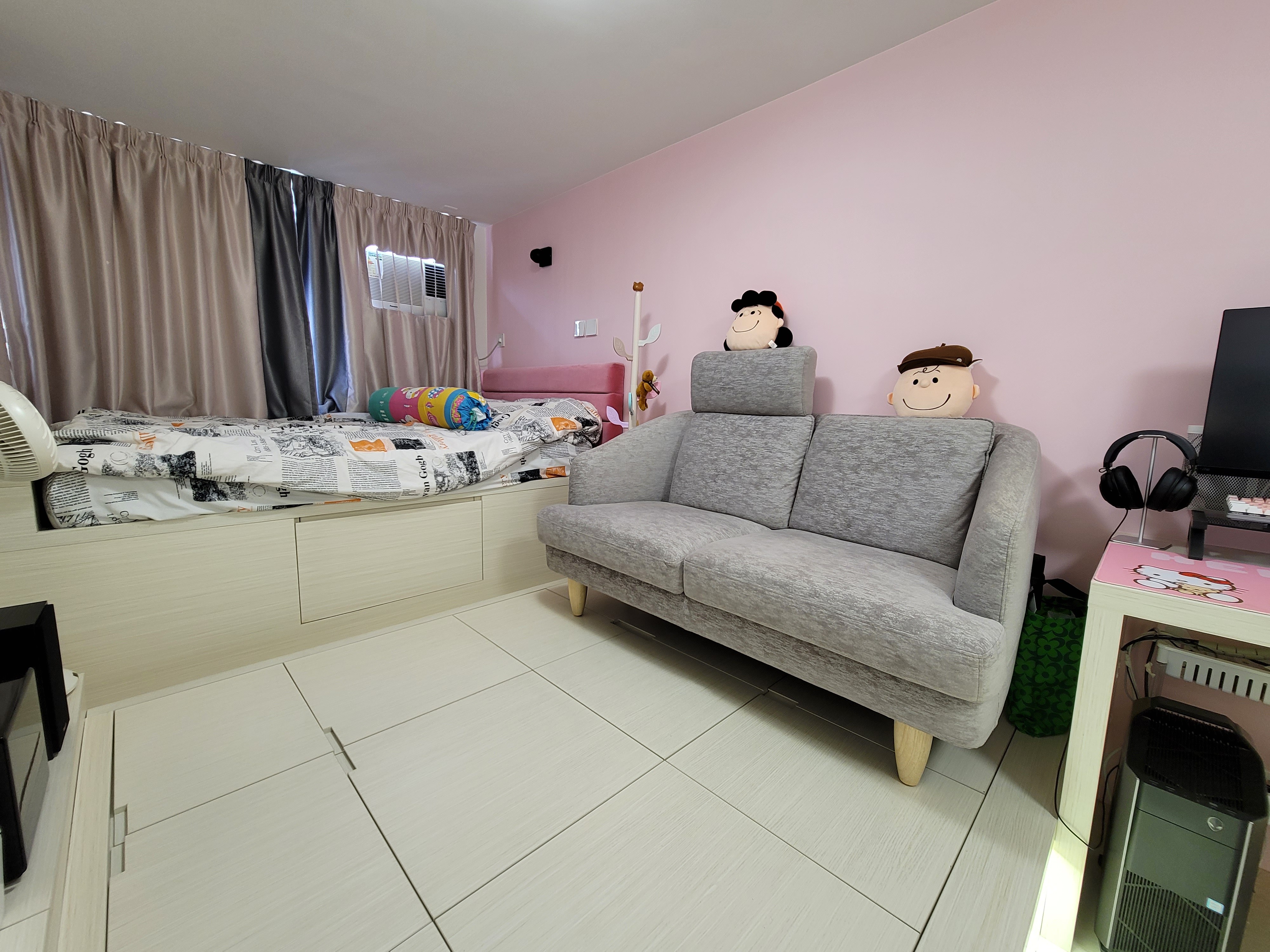 Maximizing small room efficiency at Hoi Tat Estate, this open-plan layout seamlessly connects a custom Hello Kitty kitchen to a vibrant living and dining room. The space is anchored by a sleek grey sofa with quirky character plushies, beautifully offset by custom surfaces finished in premium pink Farrow & Ball paint.