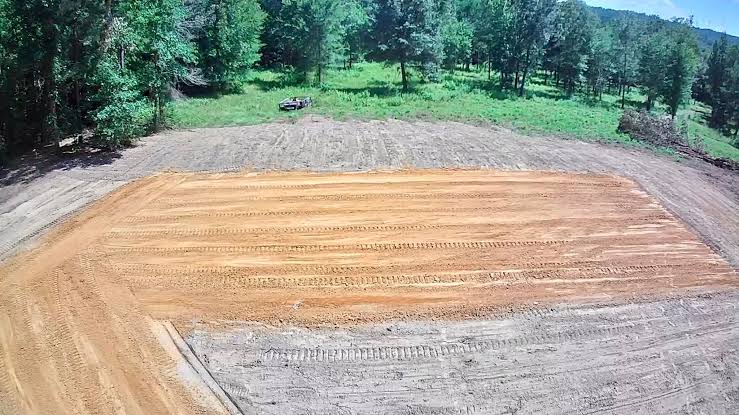 Site prep underway for a shop building pad, with topsoil stripped to bare clay.