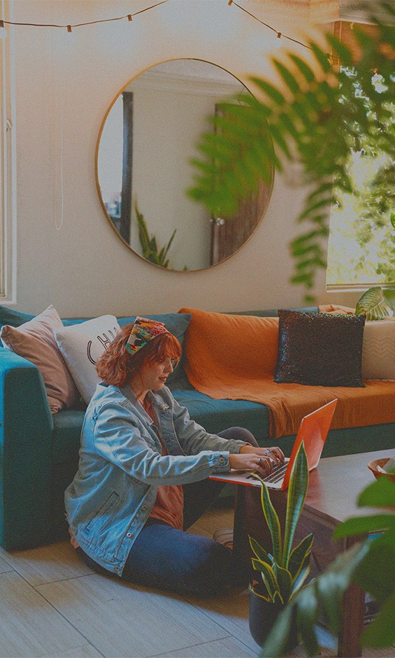 Therapist sitting on the floor in her office using her computer next to couch