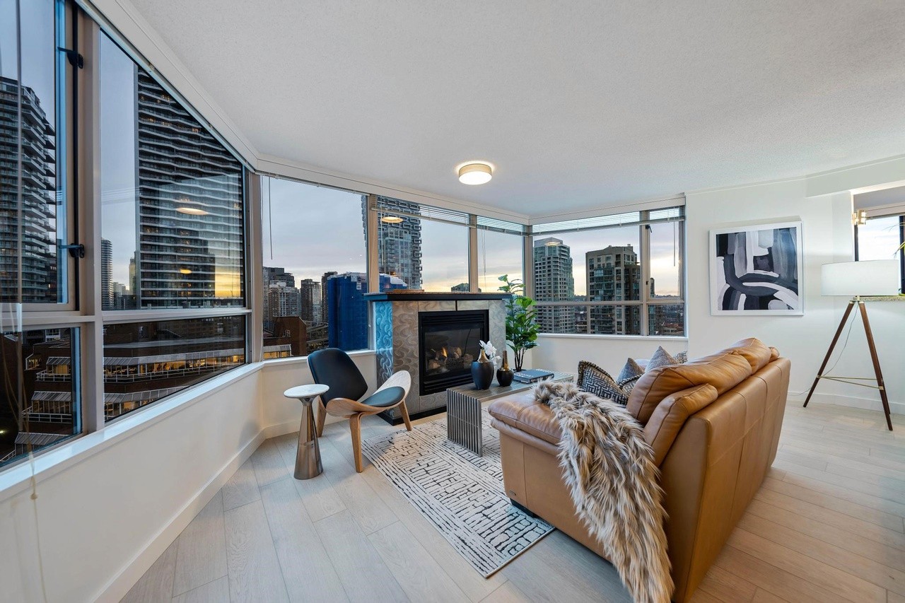 A modern living room with large windows, comfortable seating, and a view of a city skyline.