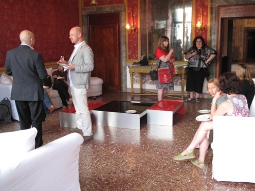 A photo of a group of people sitting in a hotel hall and talking.