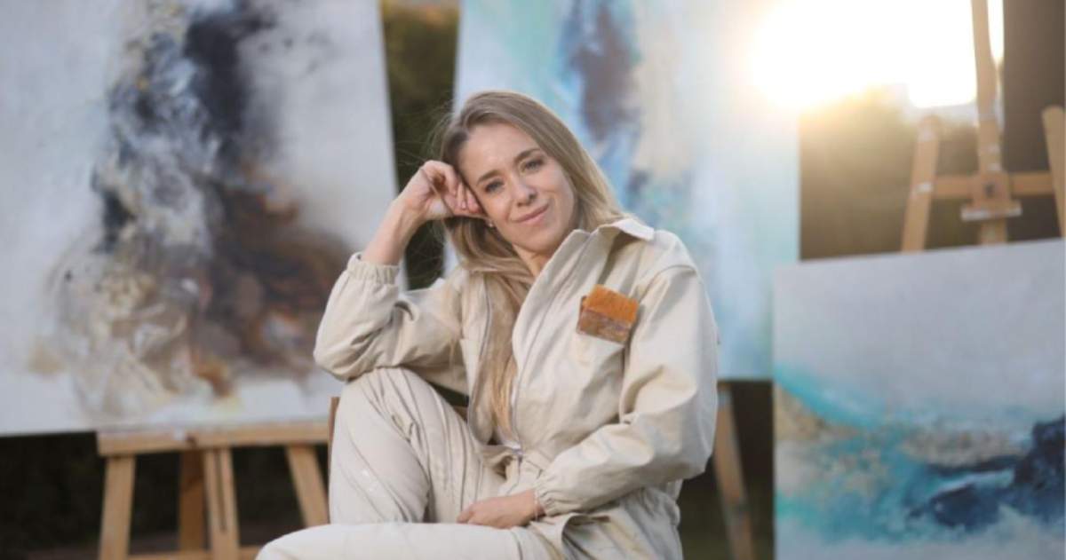 Lorena Matarraz sitting outside with her paintings