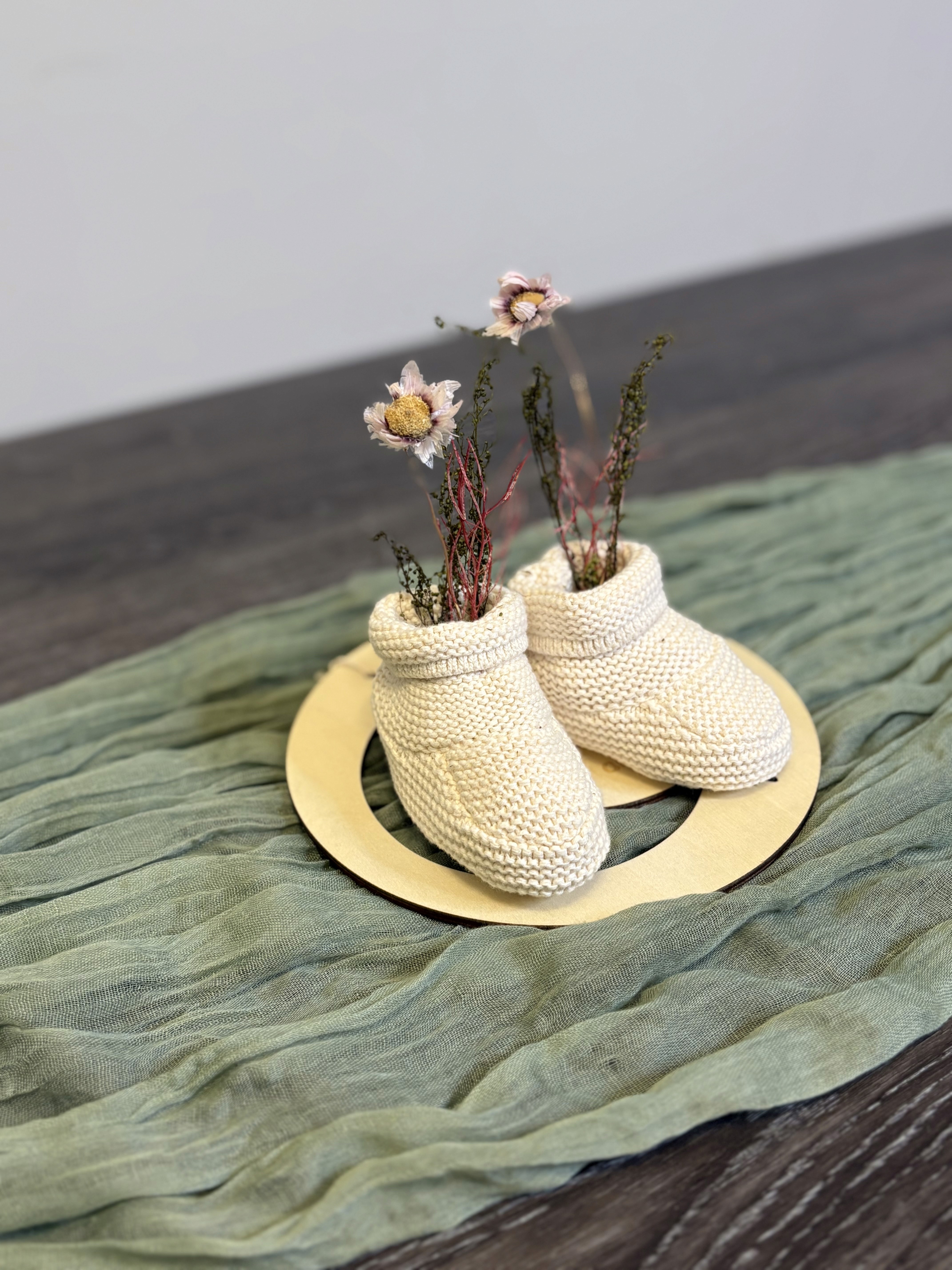 Baby booties made out of wool. the baby booties are used as a vase