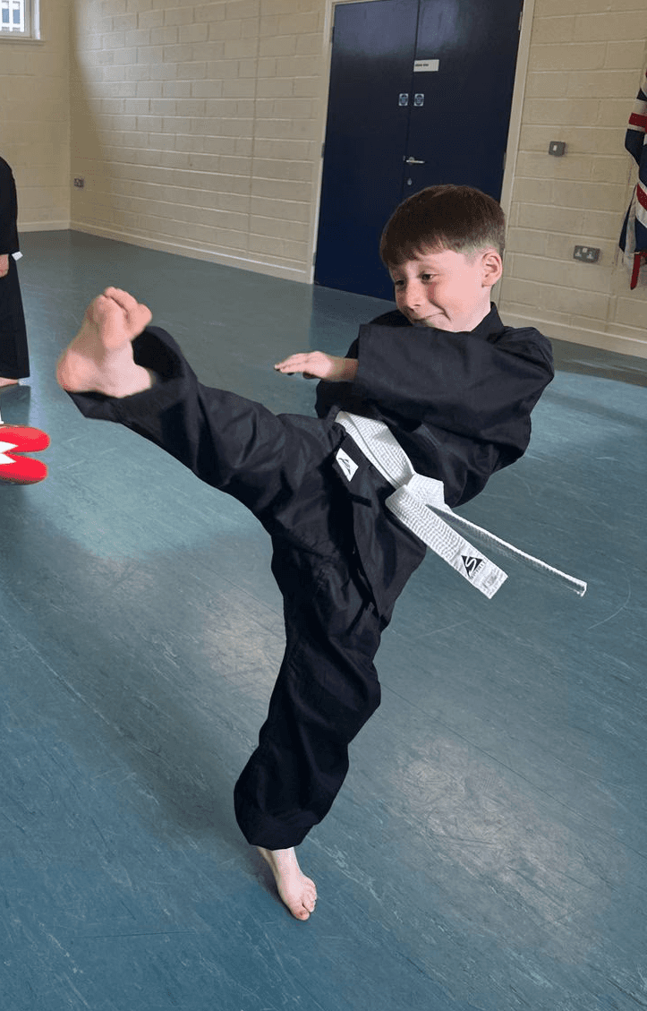 A child kicks a red target with focus and determination.
