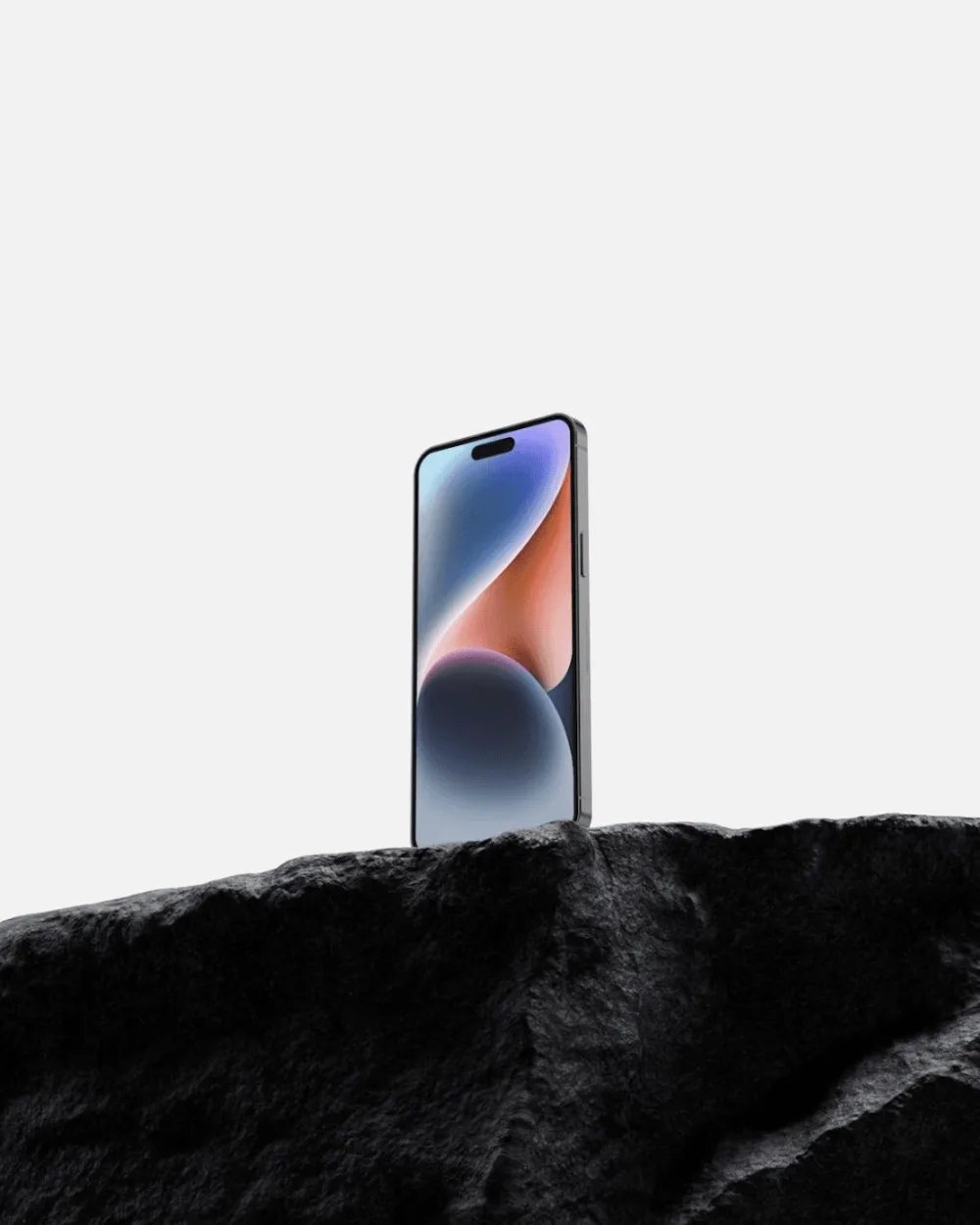 A sleek smartphone with a vibrant display featuring gradient colors, standing upright on a textured black rock surface against a minimalist white background.