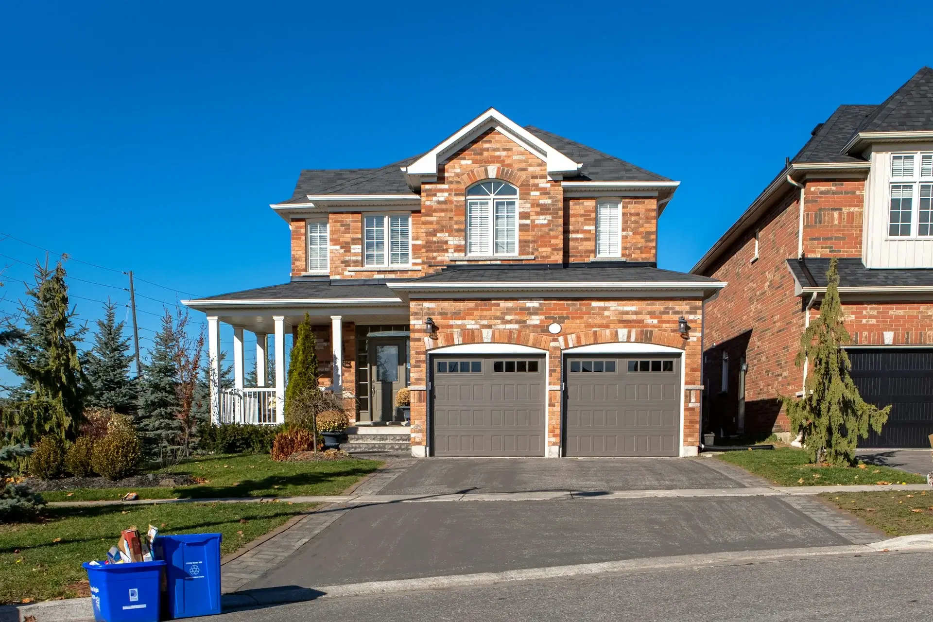 Two-story brick house with a double garage, front porch, symmetrical windows, and a neat suburban driveway.
