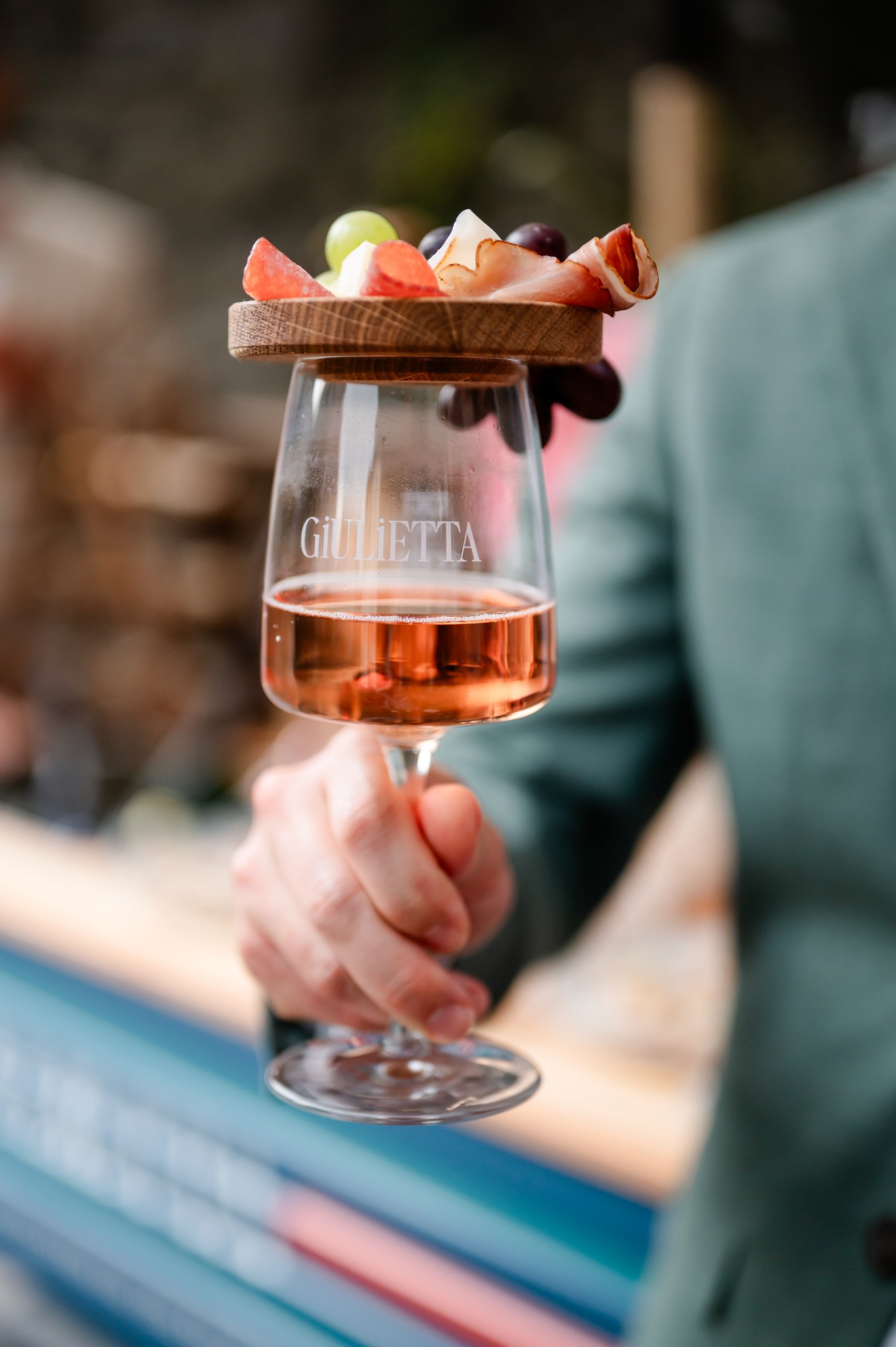 Elegante Detailansicht eines gravierten 'Giulietta' Weinglases mit Rosé und einem Holz-Häppchen-Brett für ein stilvolles Hochzeits-Aperitif.