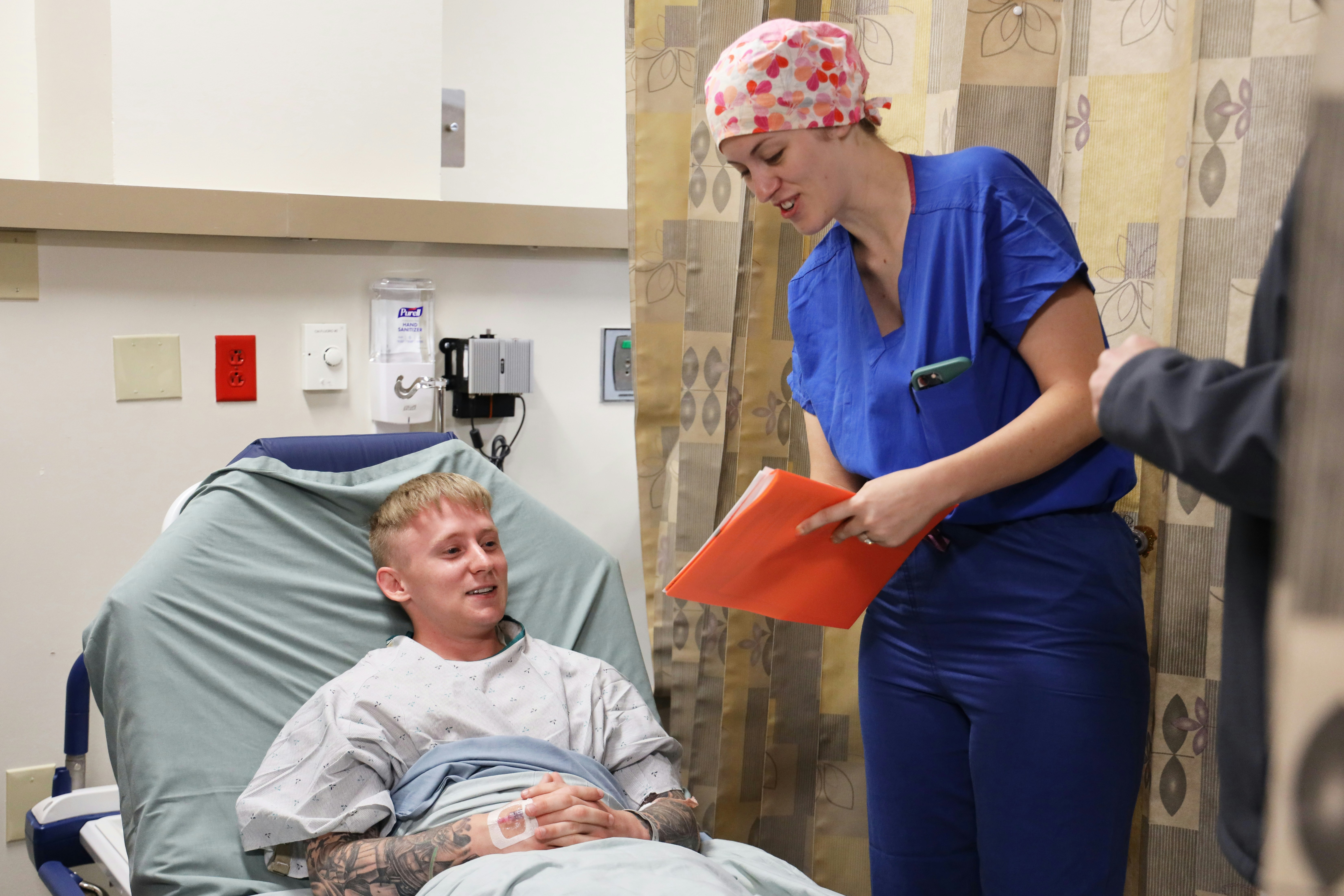 Nurse talking to patient in hospital bed.