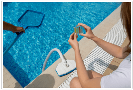 Person checking pool water chemistry with a test block while another person uses a leaf skimmer nearby.