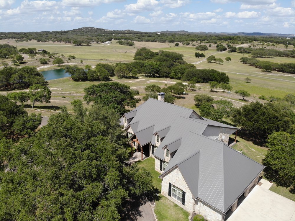 Elegant standing seam metal roof on a charming Texas countryside home, showcasing clean vertical lines and a durable, weather-resistant finish against a backdrop of lush rural landscape.